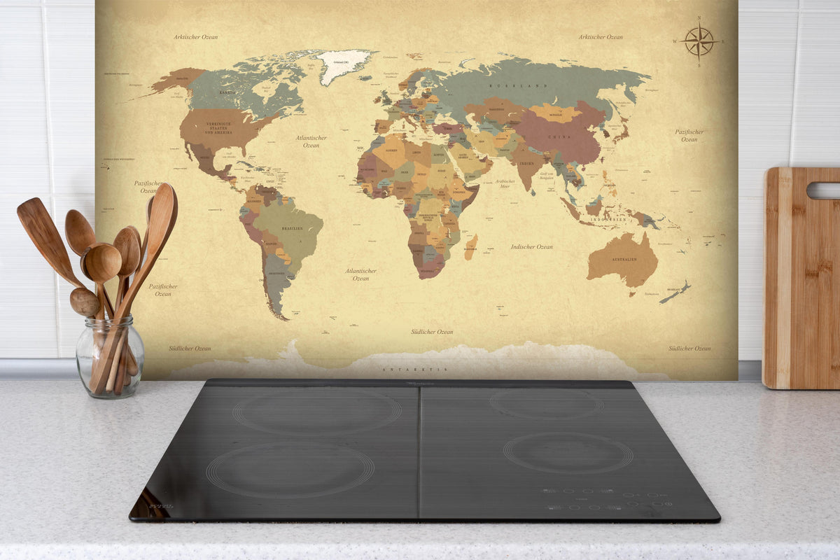 Spritzschutz - Texturierte Vintage Weltkarte in Beigetönen hinter einem Cerankochfeld zwischen Holz-Kochutensilien
