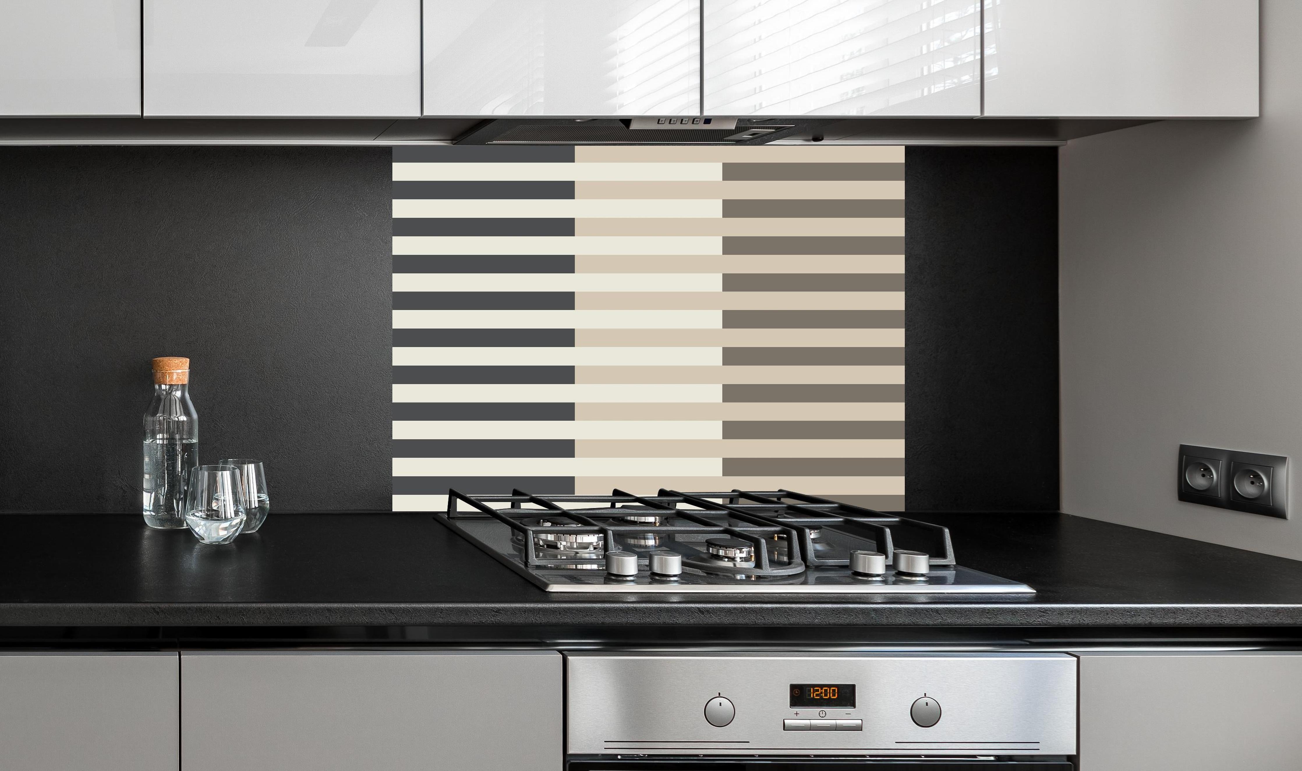 Spritzschutz - The Nudes - Multy Stripes - Toffee hinter einem Cerankochfeld zwischen Holz-Kochutensilien
