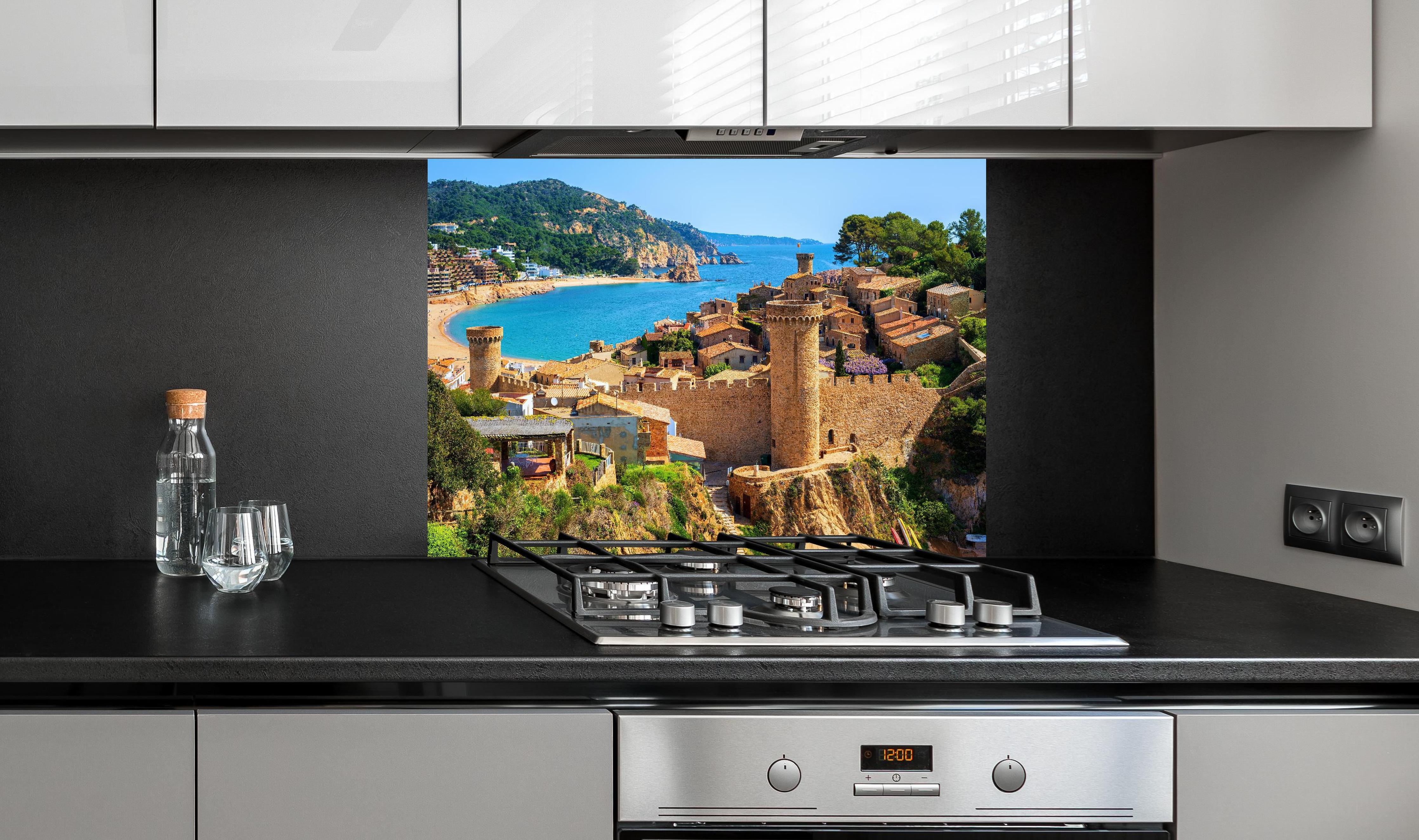 Spritzschutz - Tossa de Mar - Spanien hinter einem Cerankochfeld zwischen Holz-Kochutensilien
