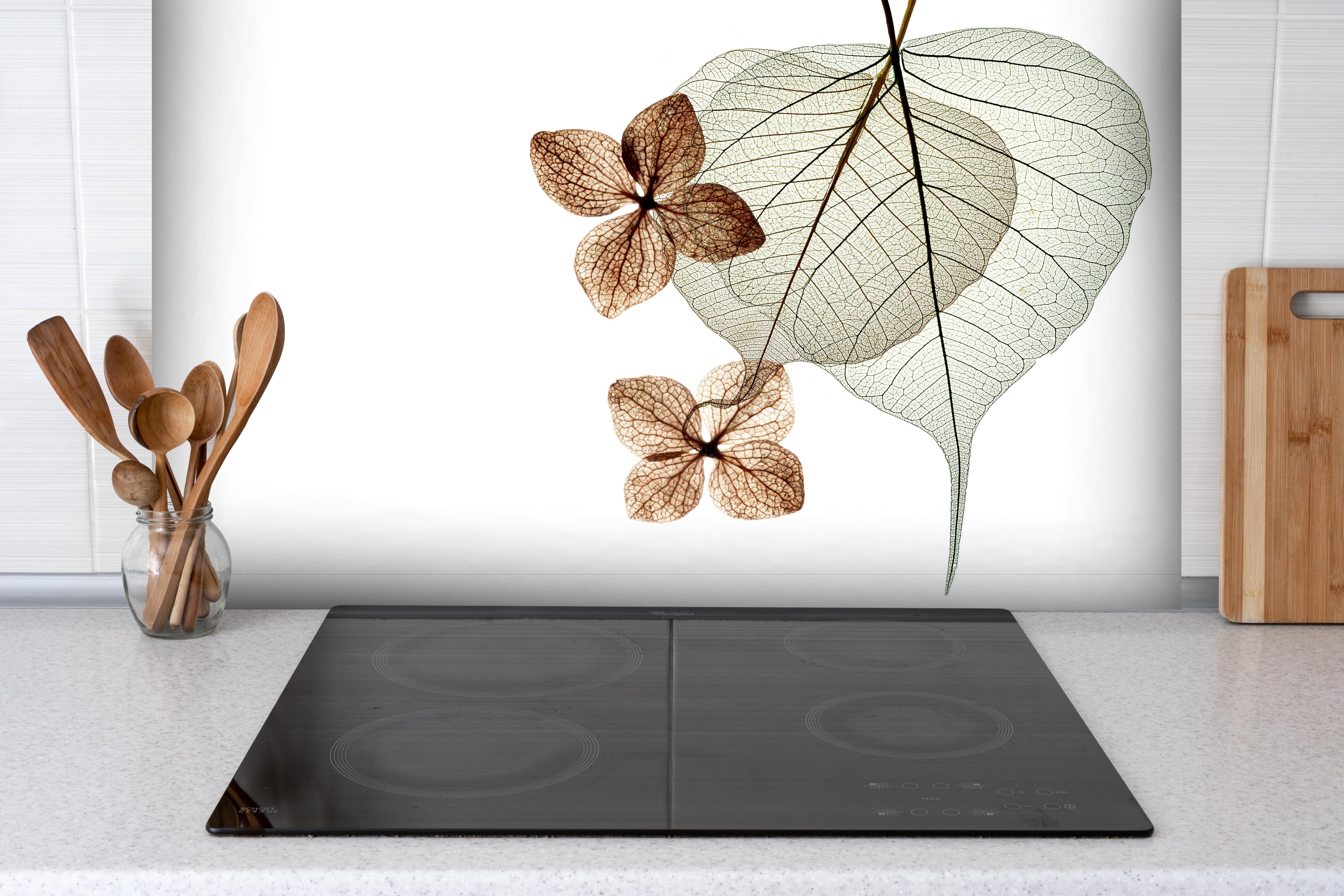 Spritzschutz - Transparente Blattstrukturen in Weiß-Grau hinter einem Cerankochfeld zwischen Holz-Kochutensilien
