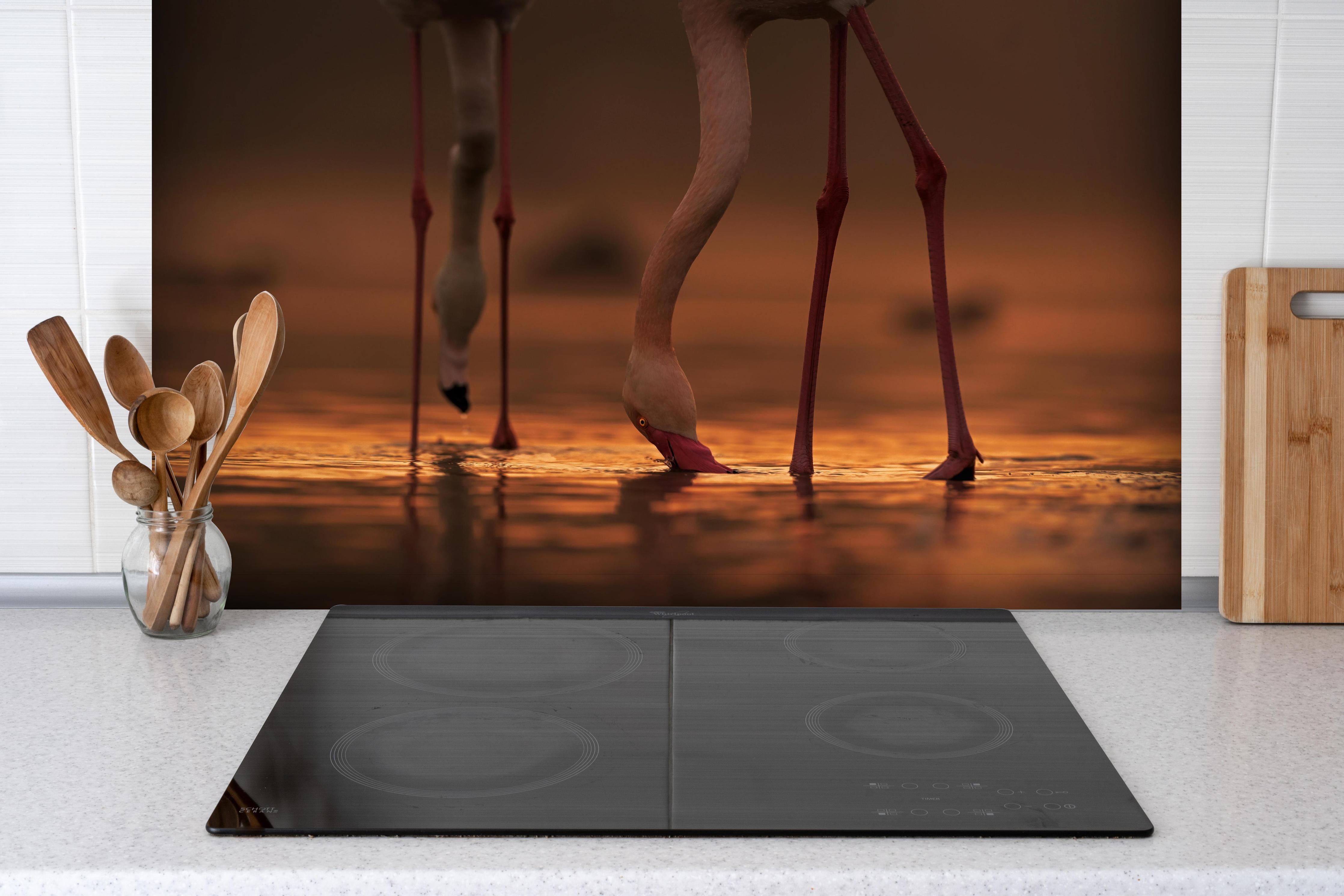 Spritzschutz - Trinkende Flamingos hinter einem Cerankochfeld zwischen Holz-Kochutensilien
