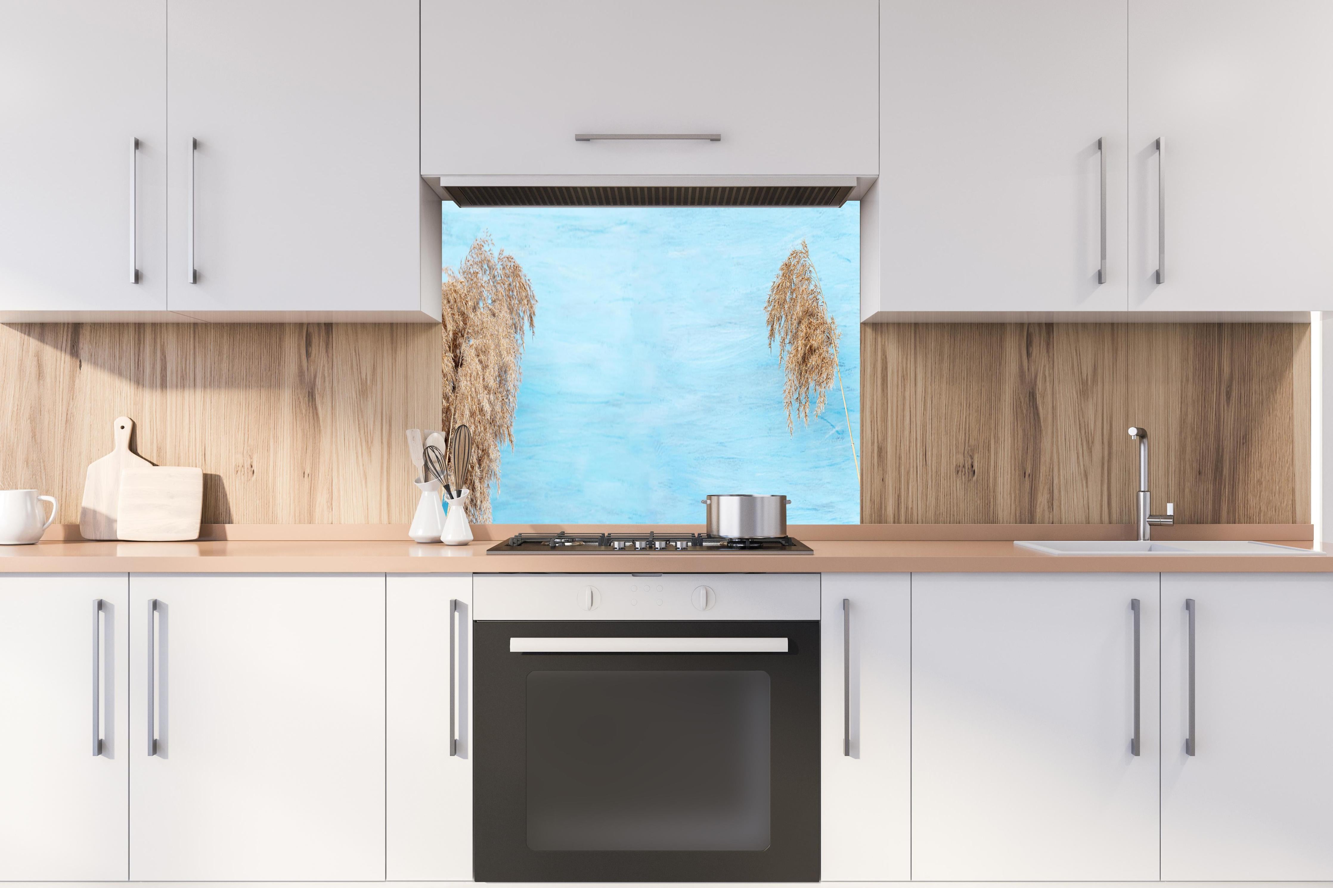 Spritzschutz - Trockene Pflanzen über dem Meer hinter einem Cerankochfeld zwischen Holz-Kochutensilien
