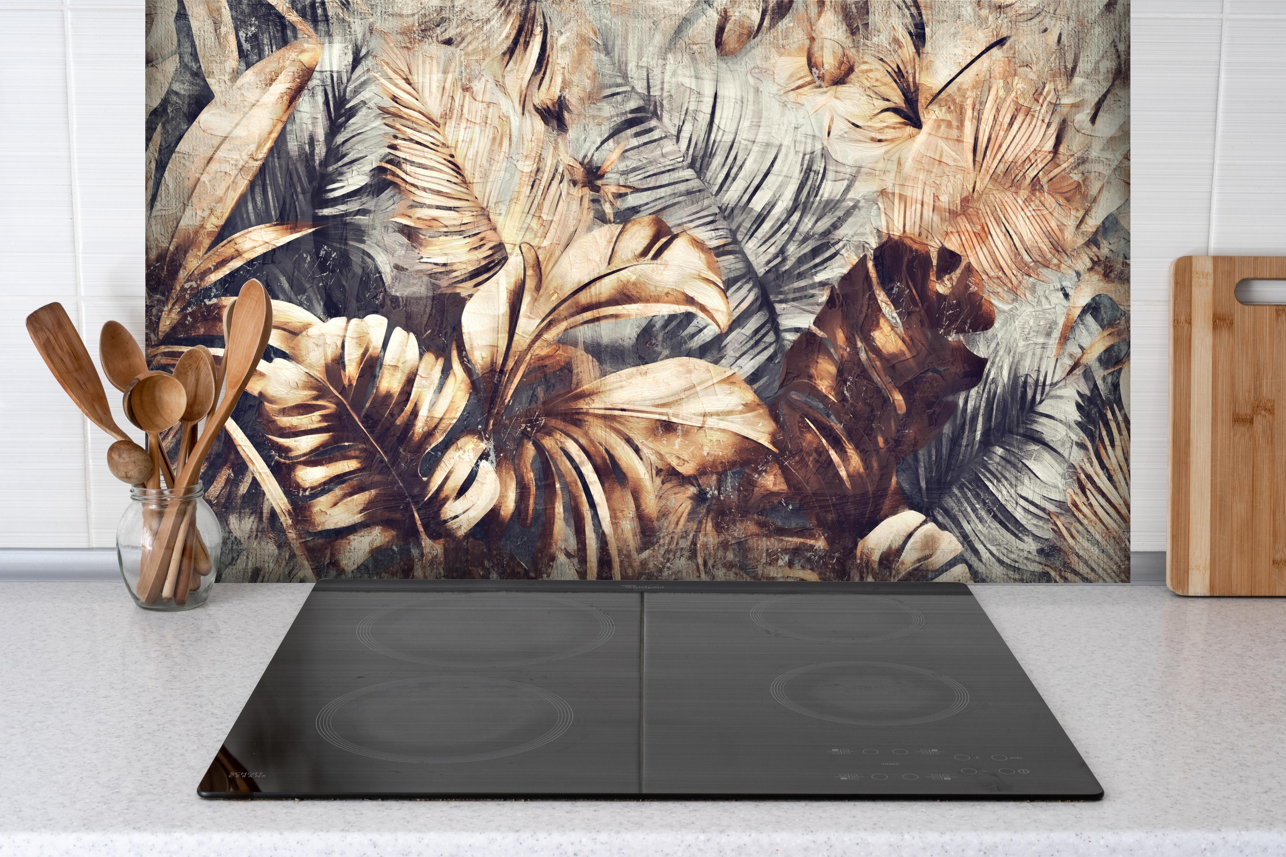 Spritzschutz - Tropische Palmenblätter in Gelb-Braun hinter einem Cerankochfeld zwischen Holz-Kochutensilien
