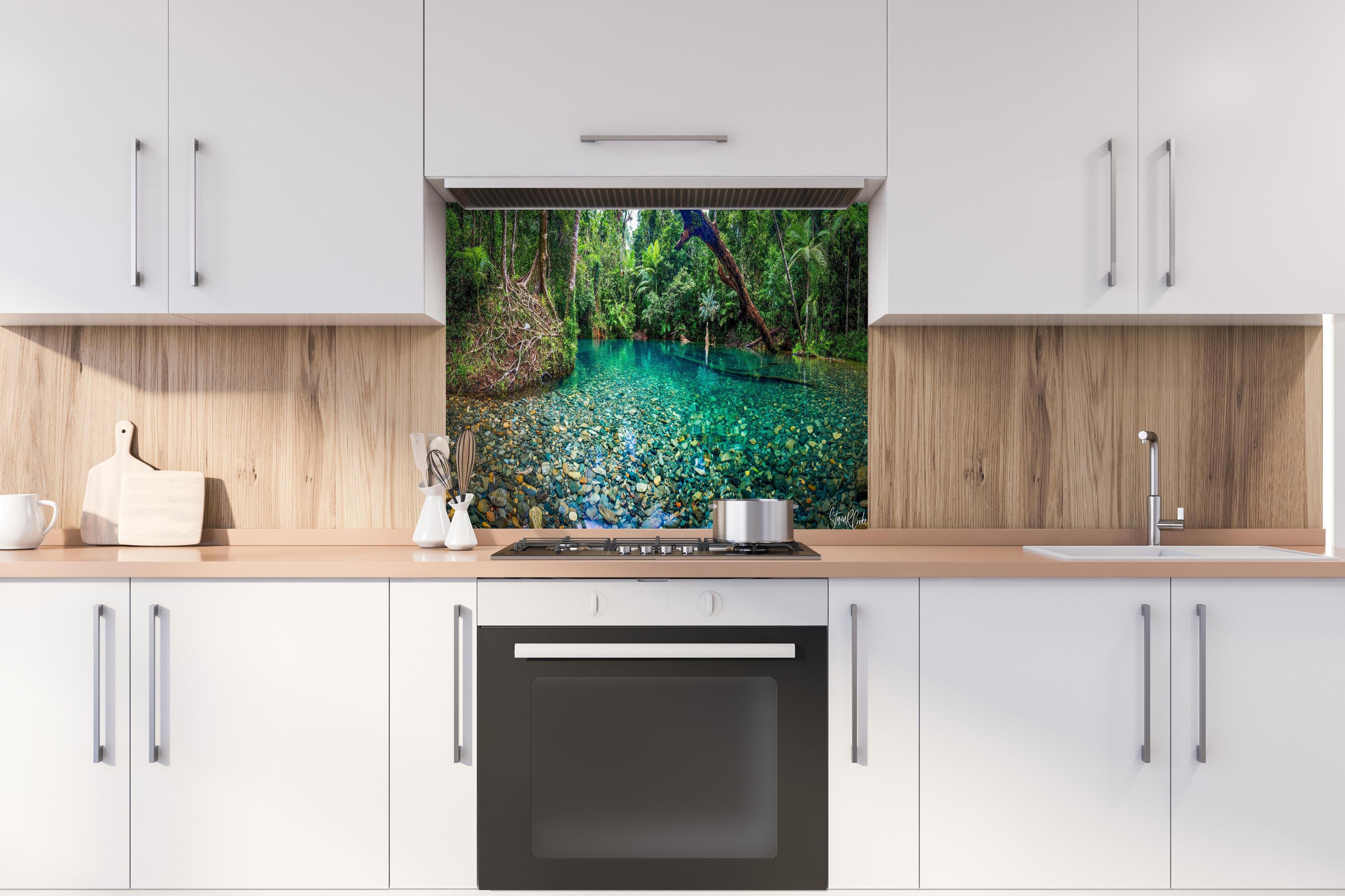 Spritzschutz - Tropischer Bach mit klarem Wasser hinter einem Cerankochfeld zwischen Holz-Kochutensilien
