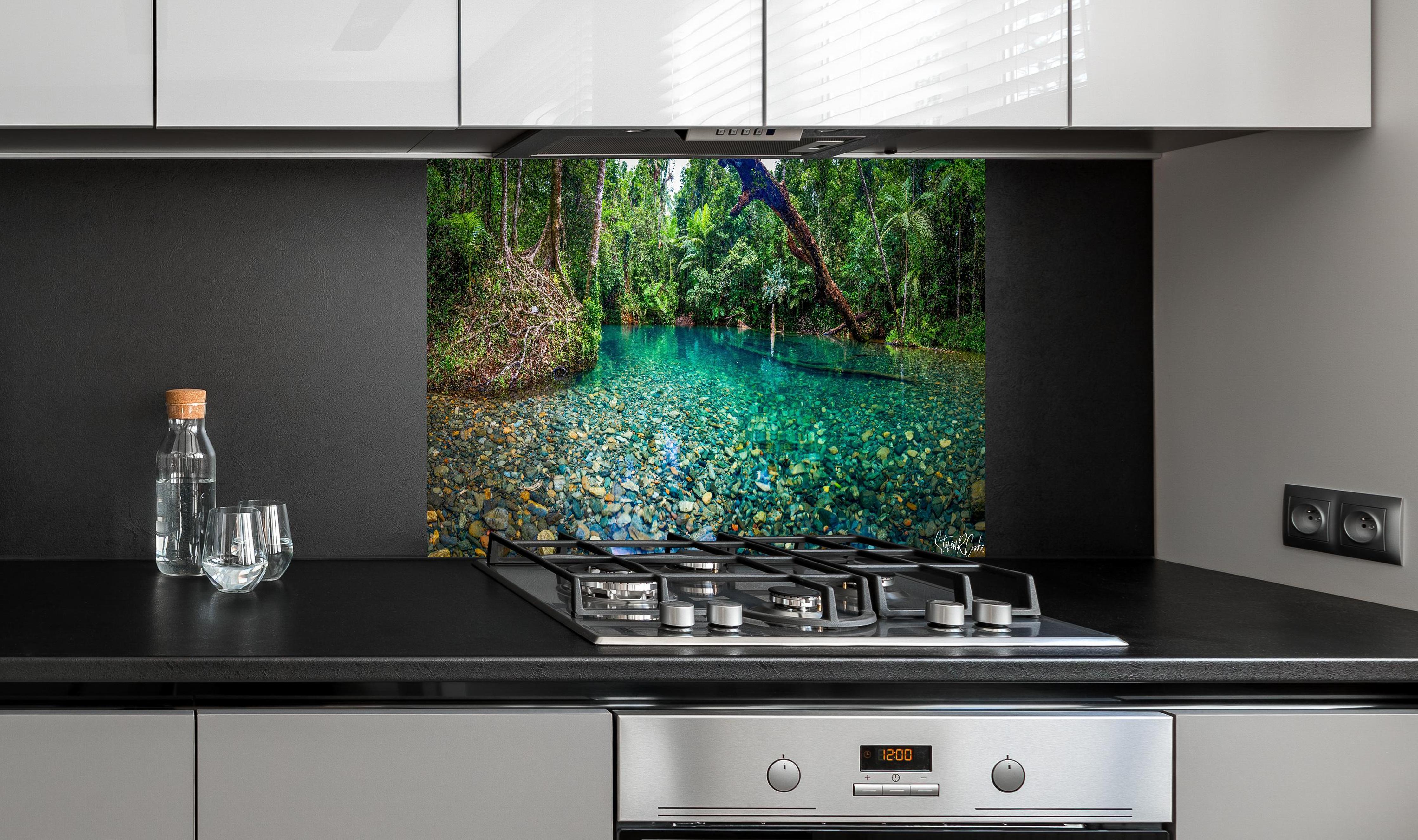 Spritzschutz - Tropischer Bach mit klarem Wasser hinter einem Cerankochfeld zwischen Holz-Kochutensilien
