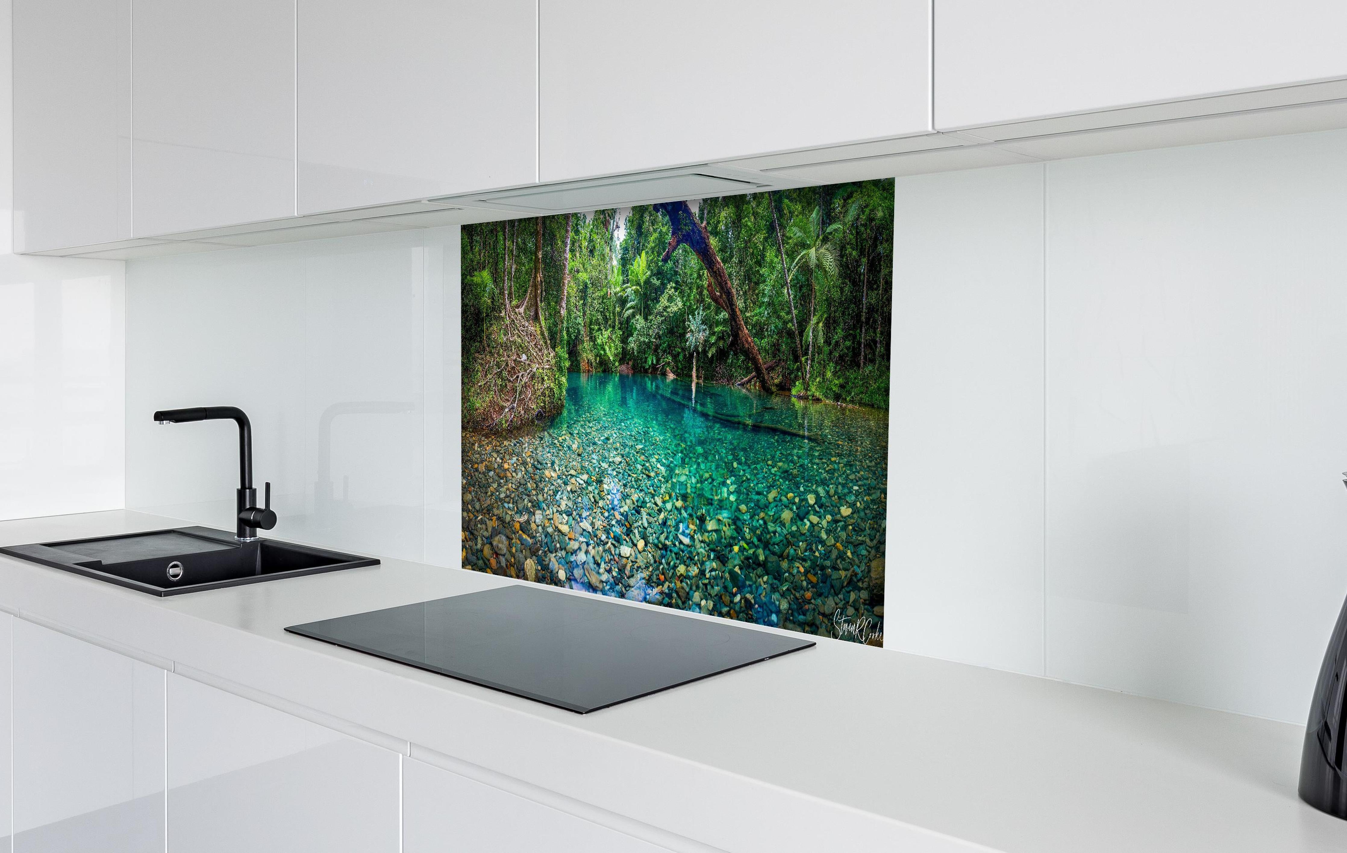 Spritzschutz - Tropischer Bach mit klarem Wasser hinter einem Cerankochfeld zwischen Holz-Kochutensilien
