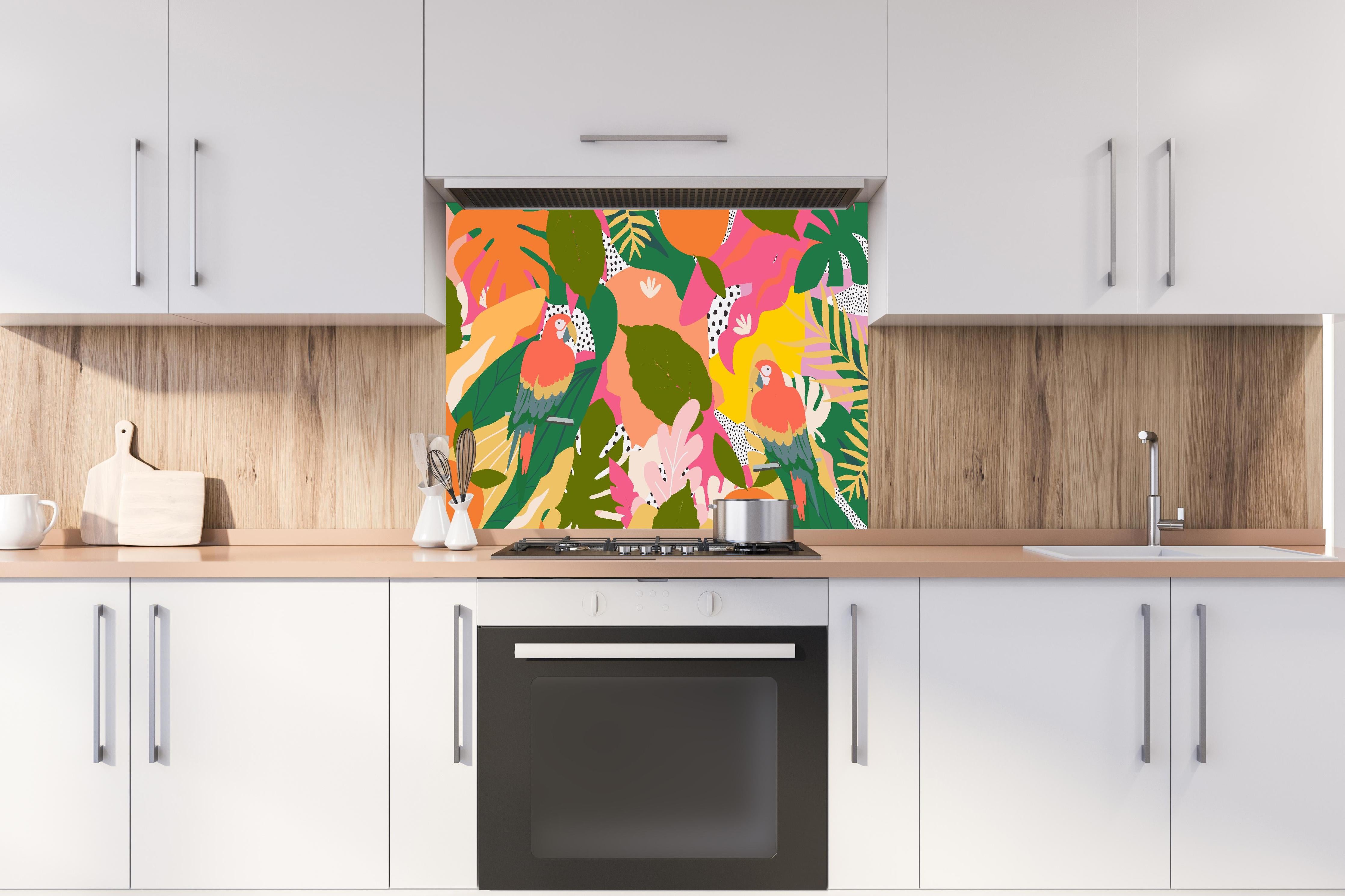 Spritzschutz - Tropischer Dschungel mit bunten Papageien hinter einem Cerankochfeld zwischen Holz-Kochutensilien
