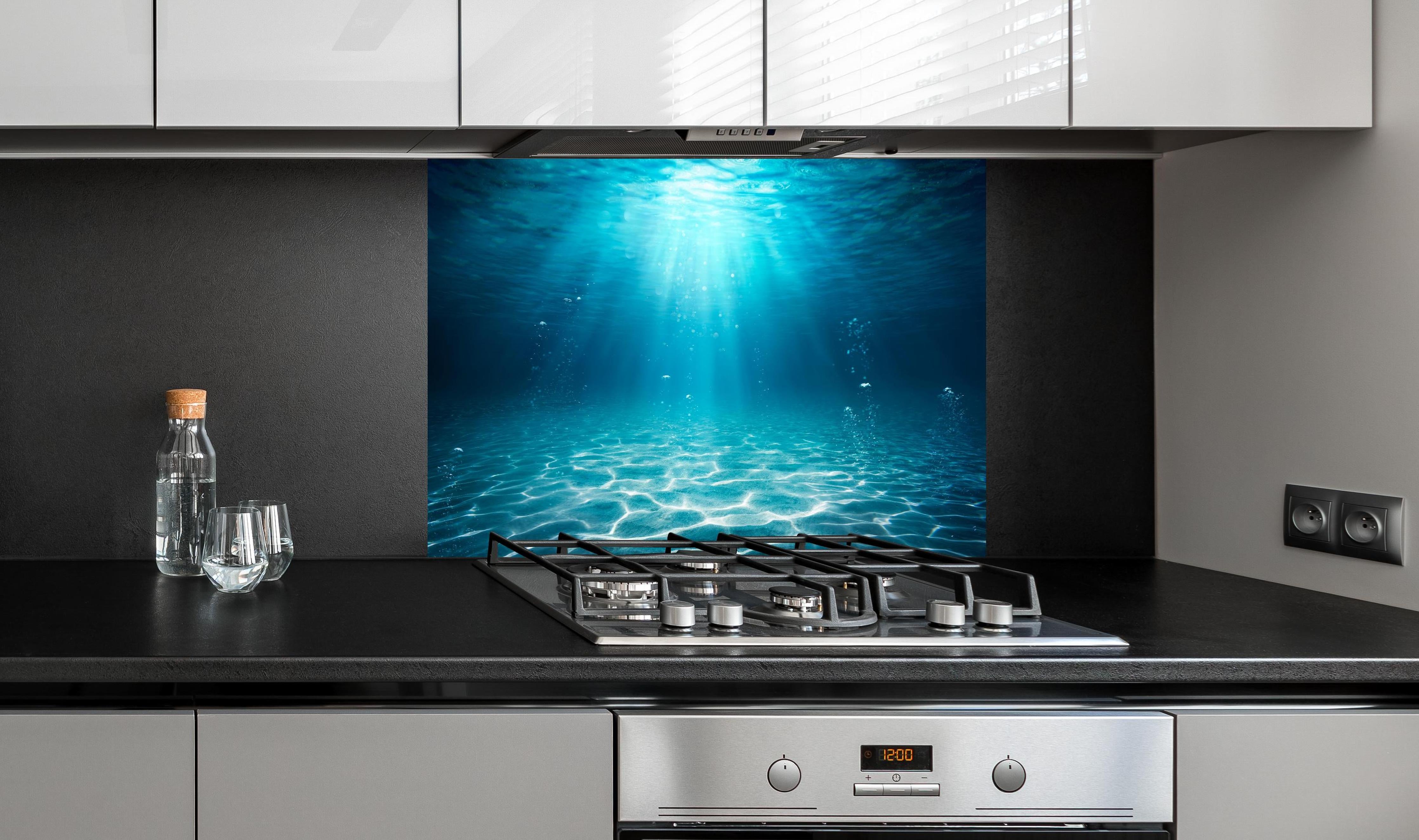 Spritzschutz - Unterwasser Blick - Ozean hinter einem Cerankochfeld zwischen Holz-Kochutensilien
