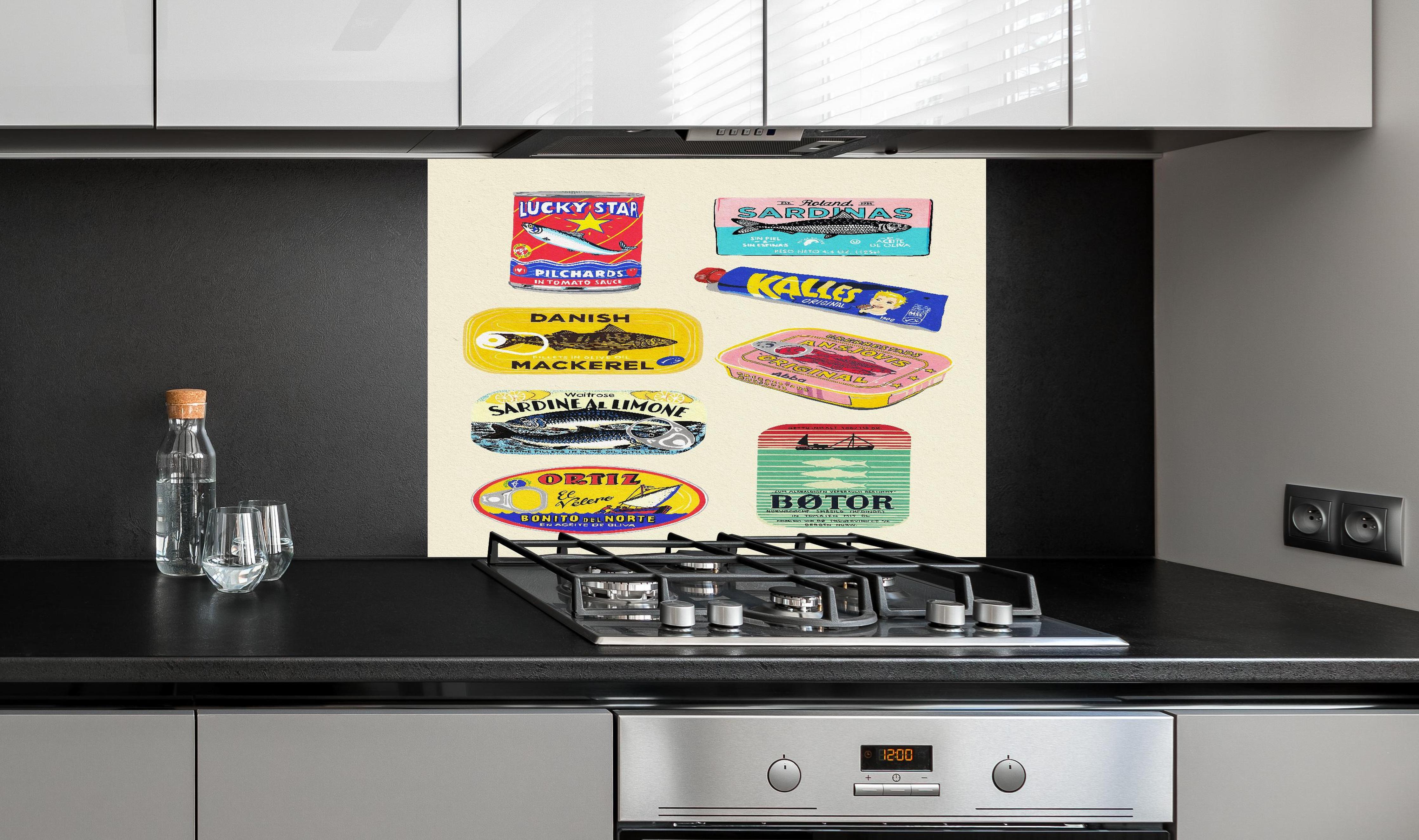 Spritzschutz - Verschiedenste Dosenfische  hinter einem Cerankochfeld zwischen Holz-Kochutensilien
