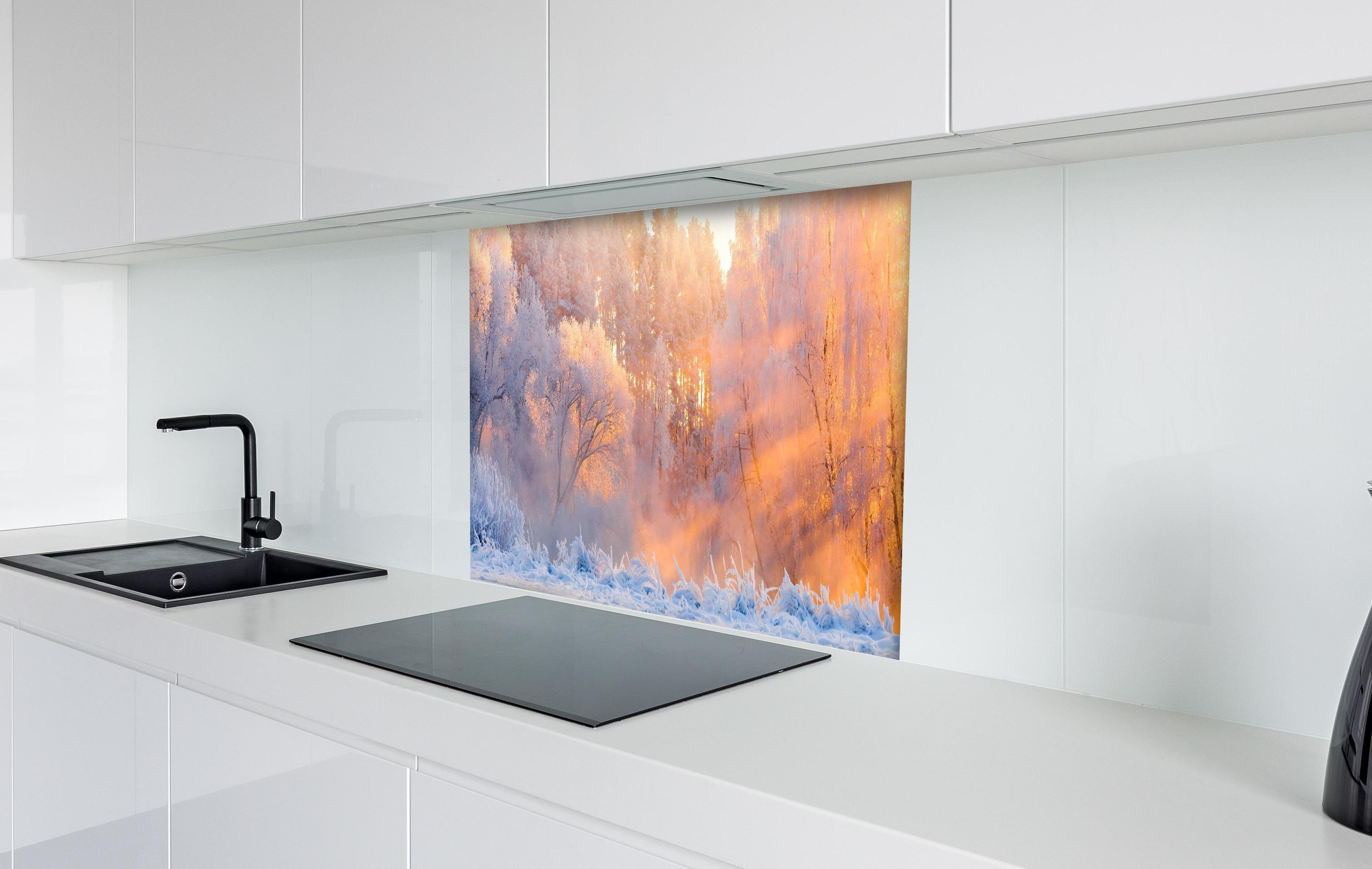 Spritzschutz - Verschneiter Wald im goldenen Morgenlicht hinter einem Cerankochfeld zwischen Holz-Kochutensilien
