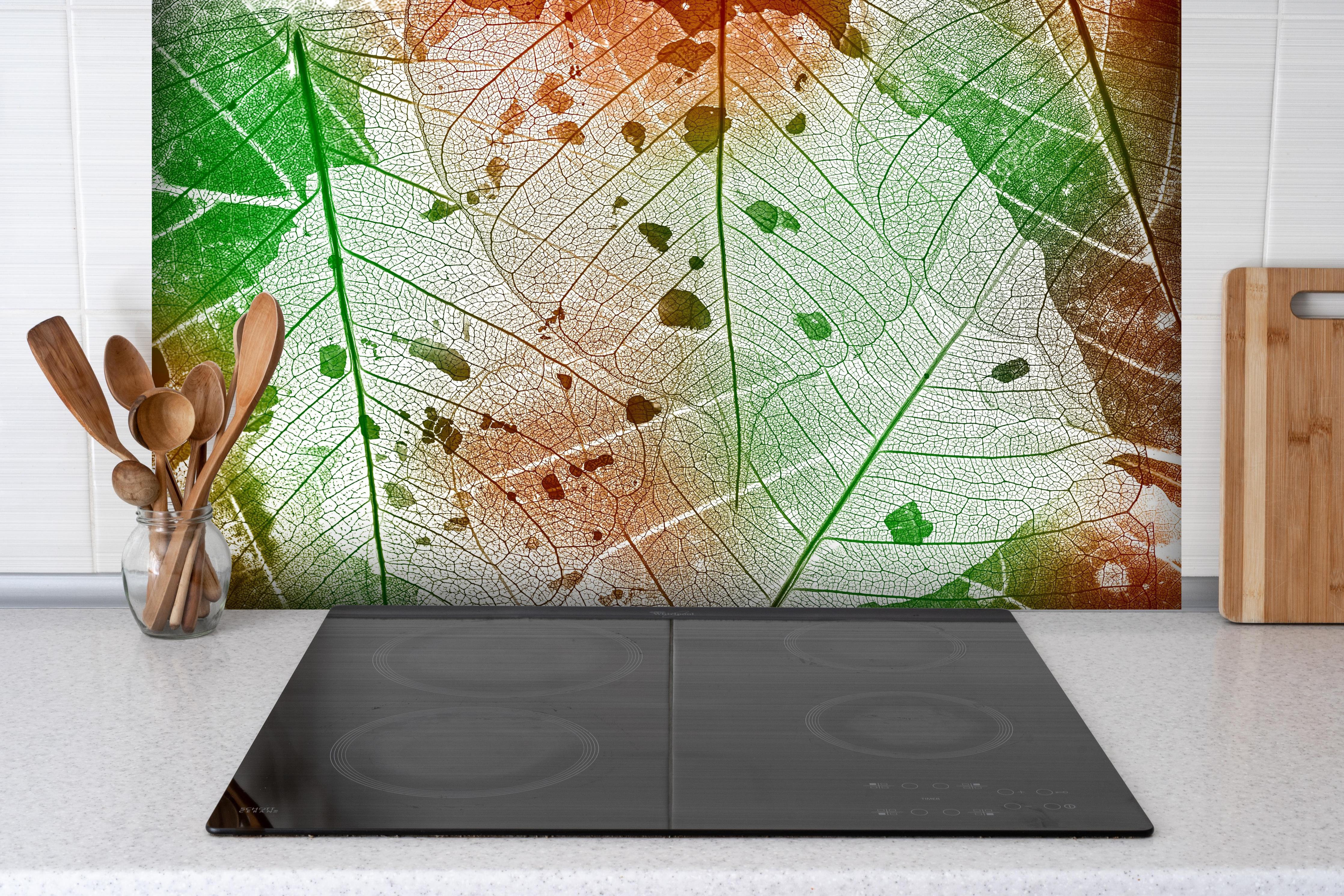 Spritzschutz - Vielfarbige Blattstruktur Detailansicht hinter einem Cerankochfeld zwischen Holz-Kochutensilien
