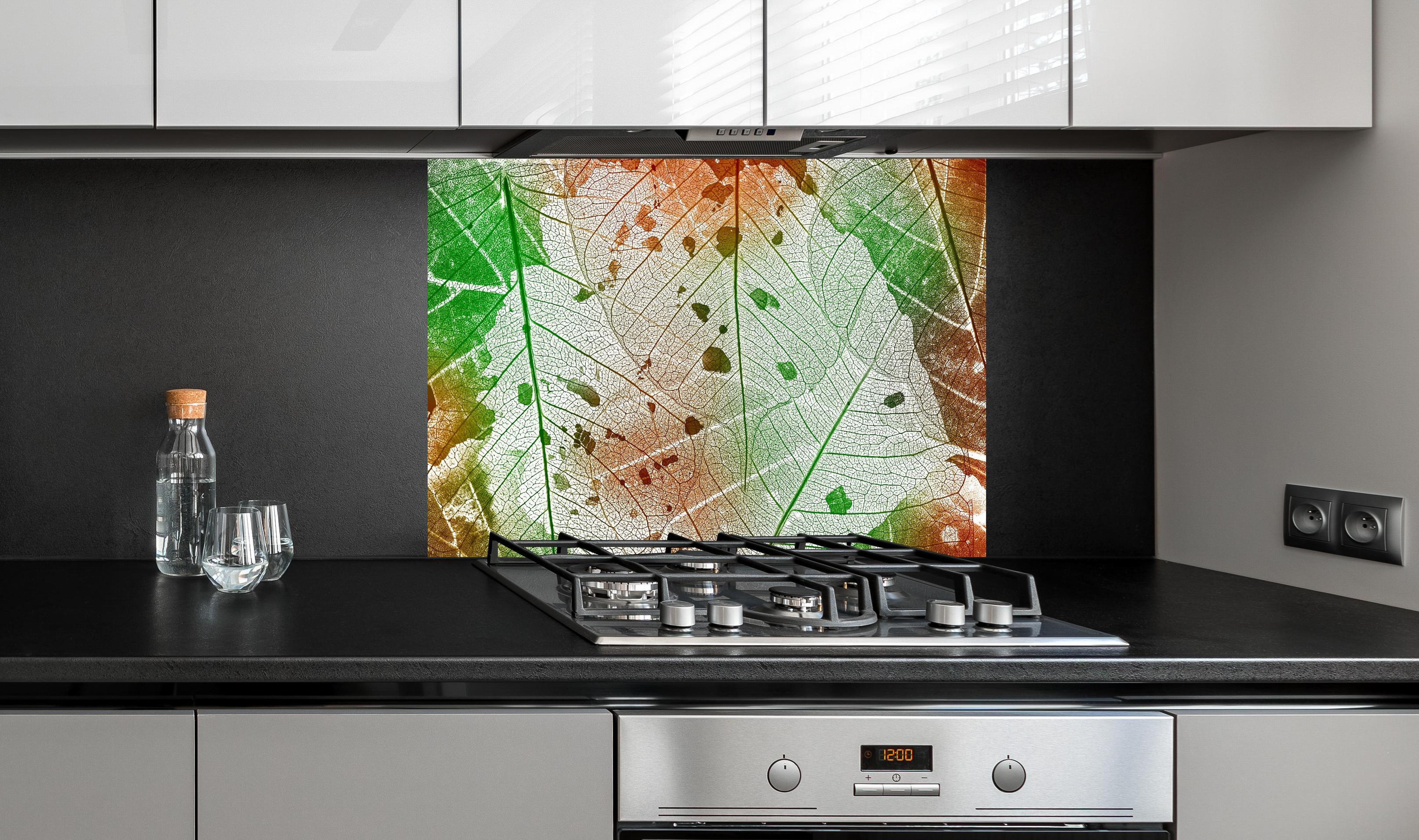 Spritzschutz - Vielfarbige Blattstruktur Detailansicht hinter einem Cerankochfeld zwischen Holz-Kochutensilien
