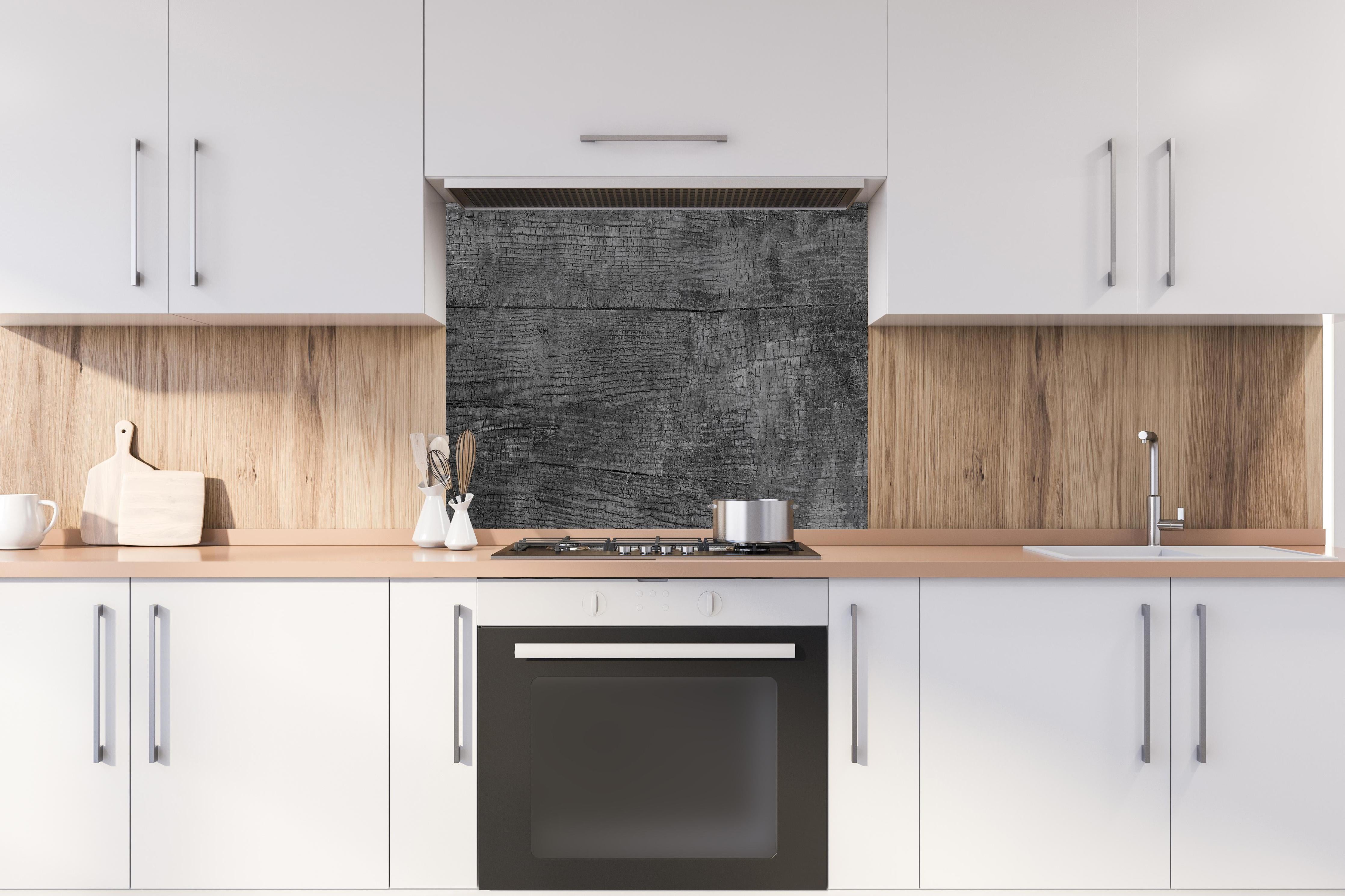 Spritzschutz - Vintage Schwarz-Graue Altholz-Textur hinter einem Cerankochfeld zwischen Holz-Kochutensilien
