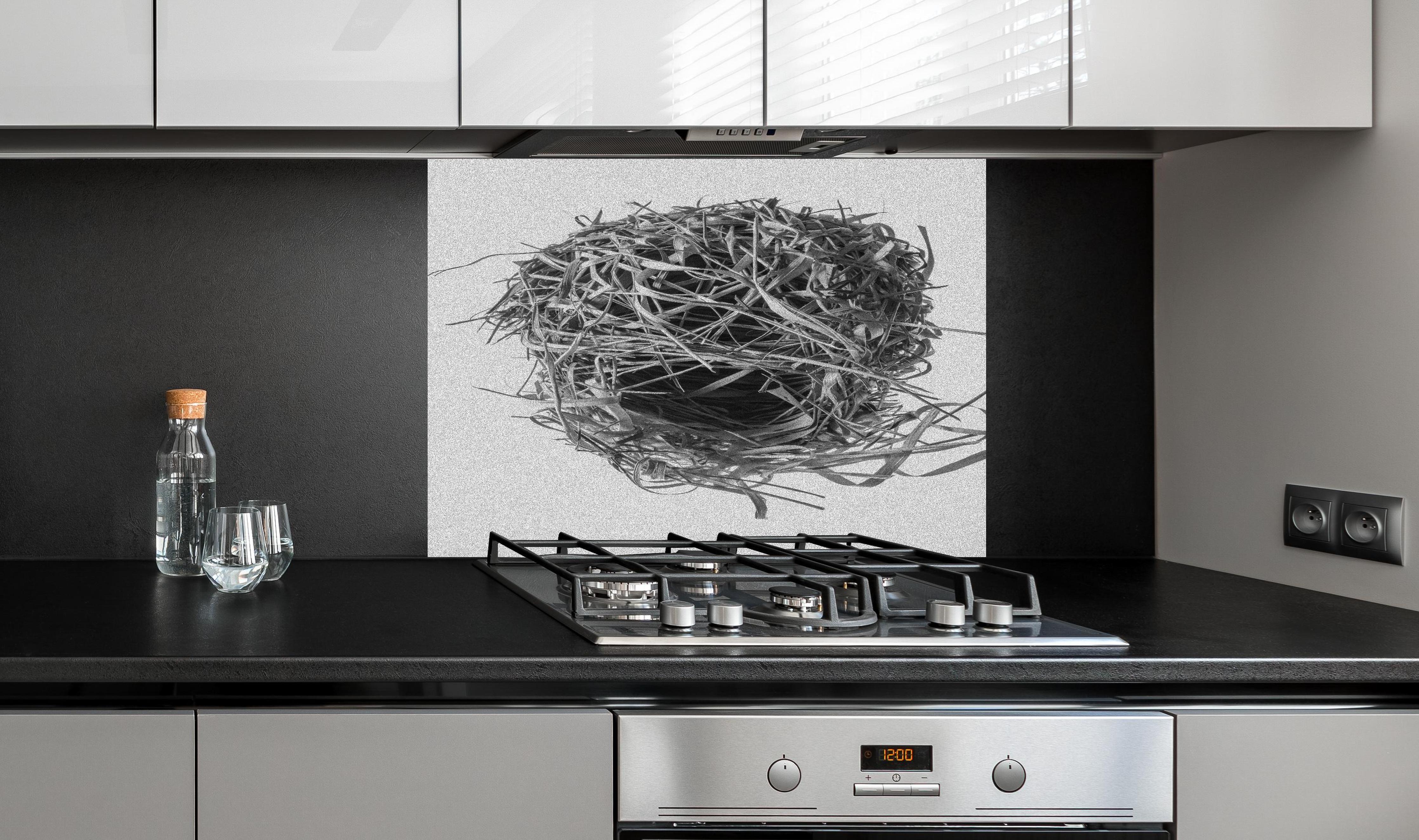 Spritzschutz - Vogelnest - schwarz-weiß hinter einem Cerankochfeld zwischen Holz-Kochutensilien
