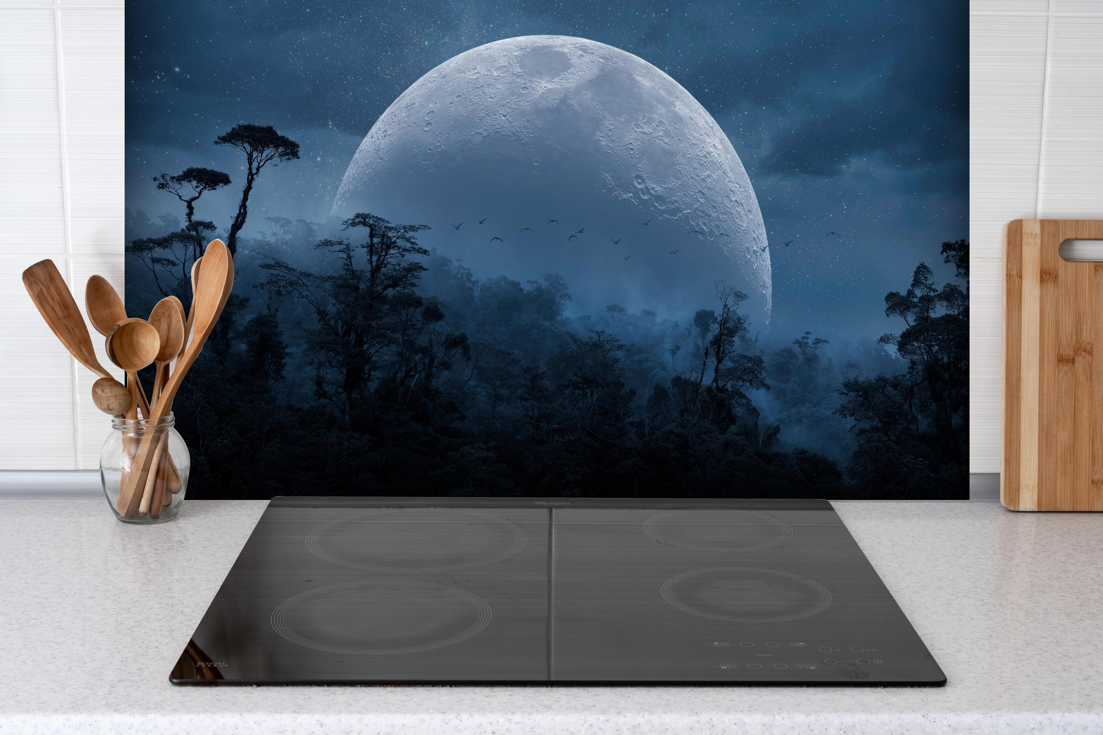 Spritzschutz - Vollmond über mystischem Dschungel hinter einem Cerankochfeld zwischen Holz-Kochutensilien
