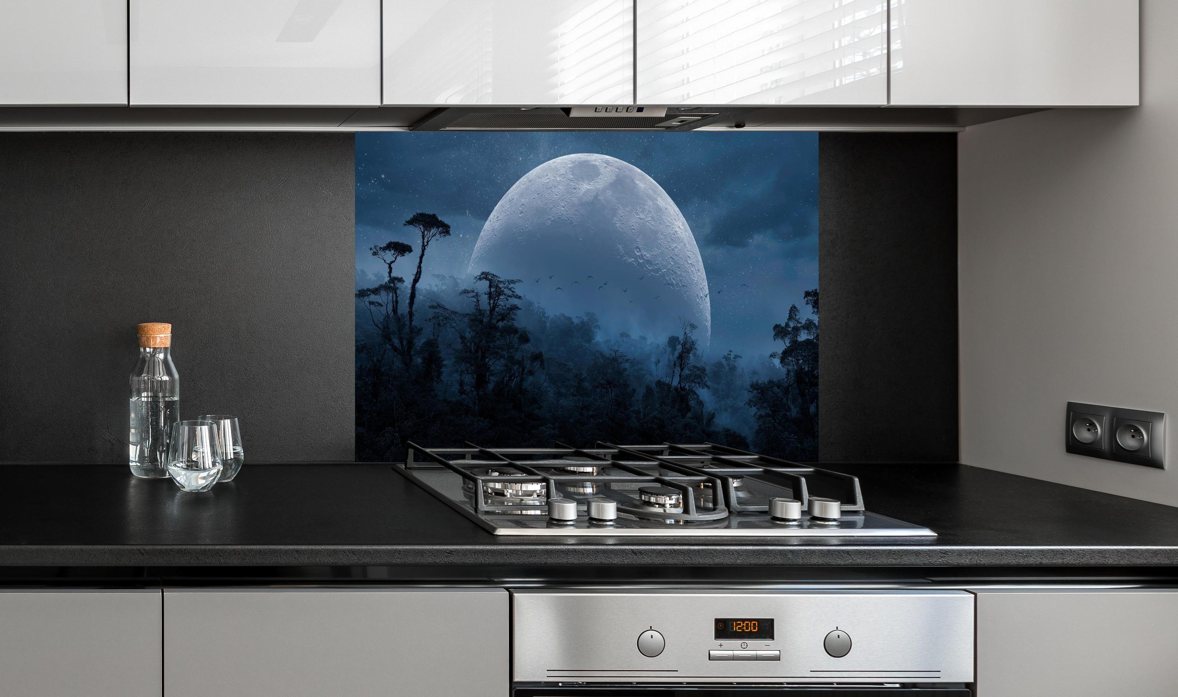 Spritzschutz - Vollmond über mystischem Dschungel hinter einem Cerankochfeld zwischen Holz-Kochutensilien
