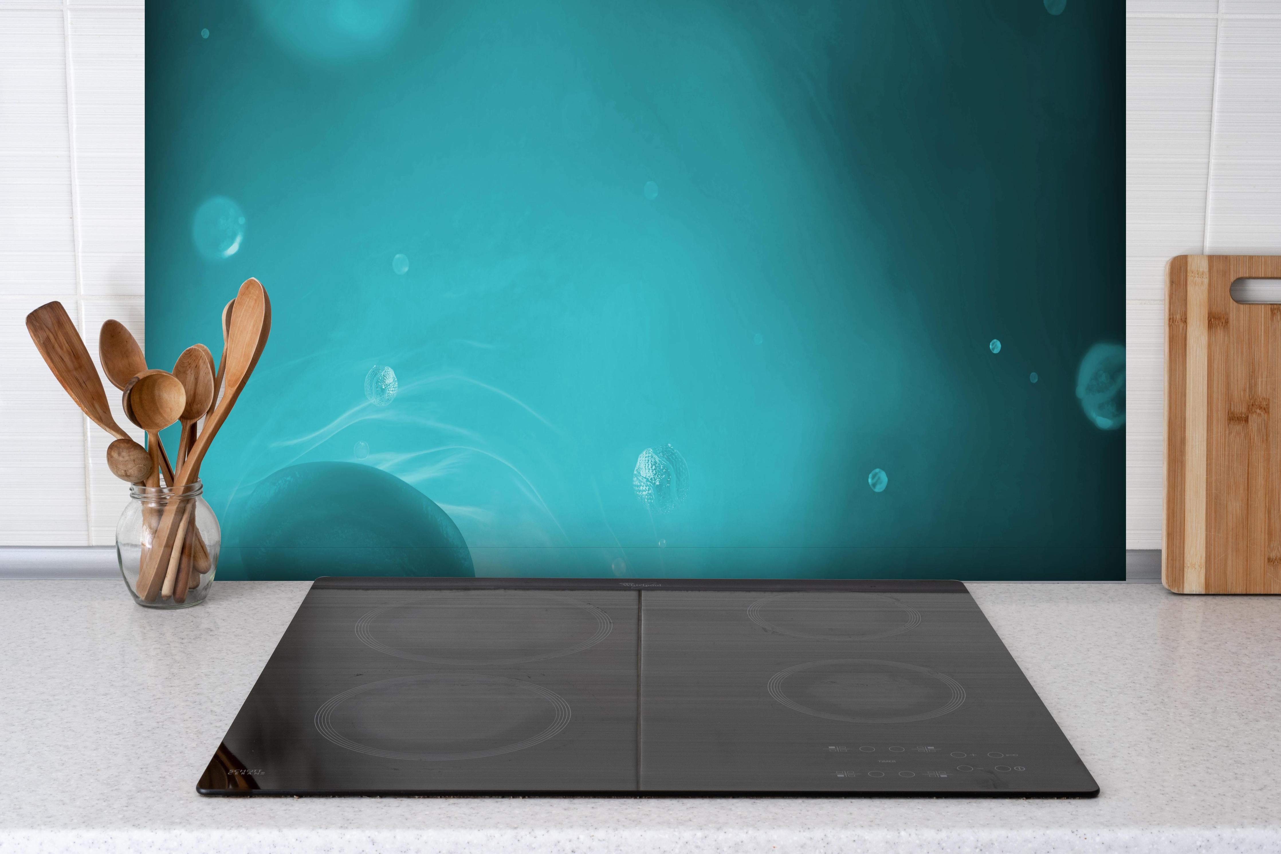 Spritzschutz - Wässriger Tauchgang hinter einem Cerankochfeld zwischen Holz-Kochutensilien
