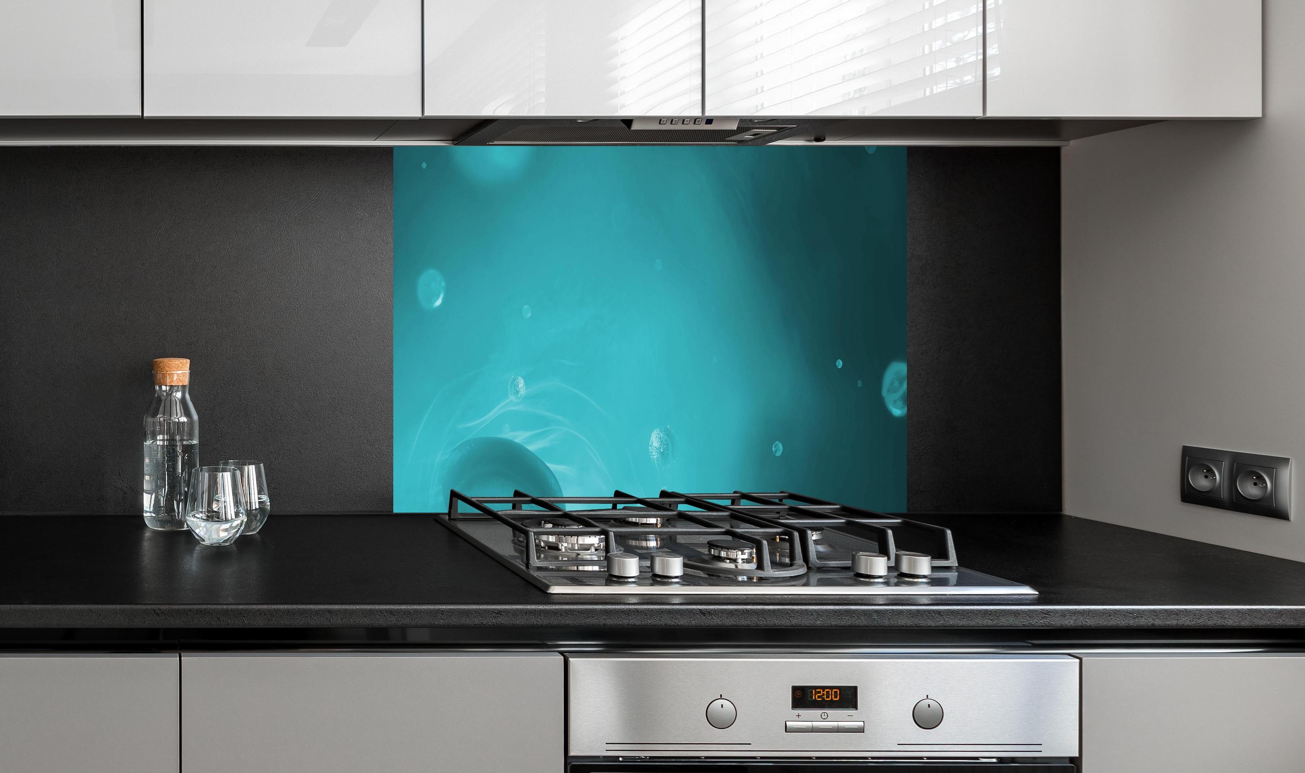 Spritzschutz - Wässriger Tauchgang hinter einem Cerankochfeld zwischen Holz-Kochutensilien
