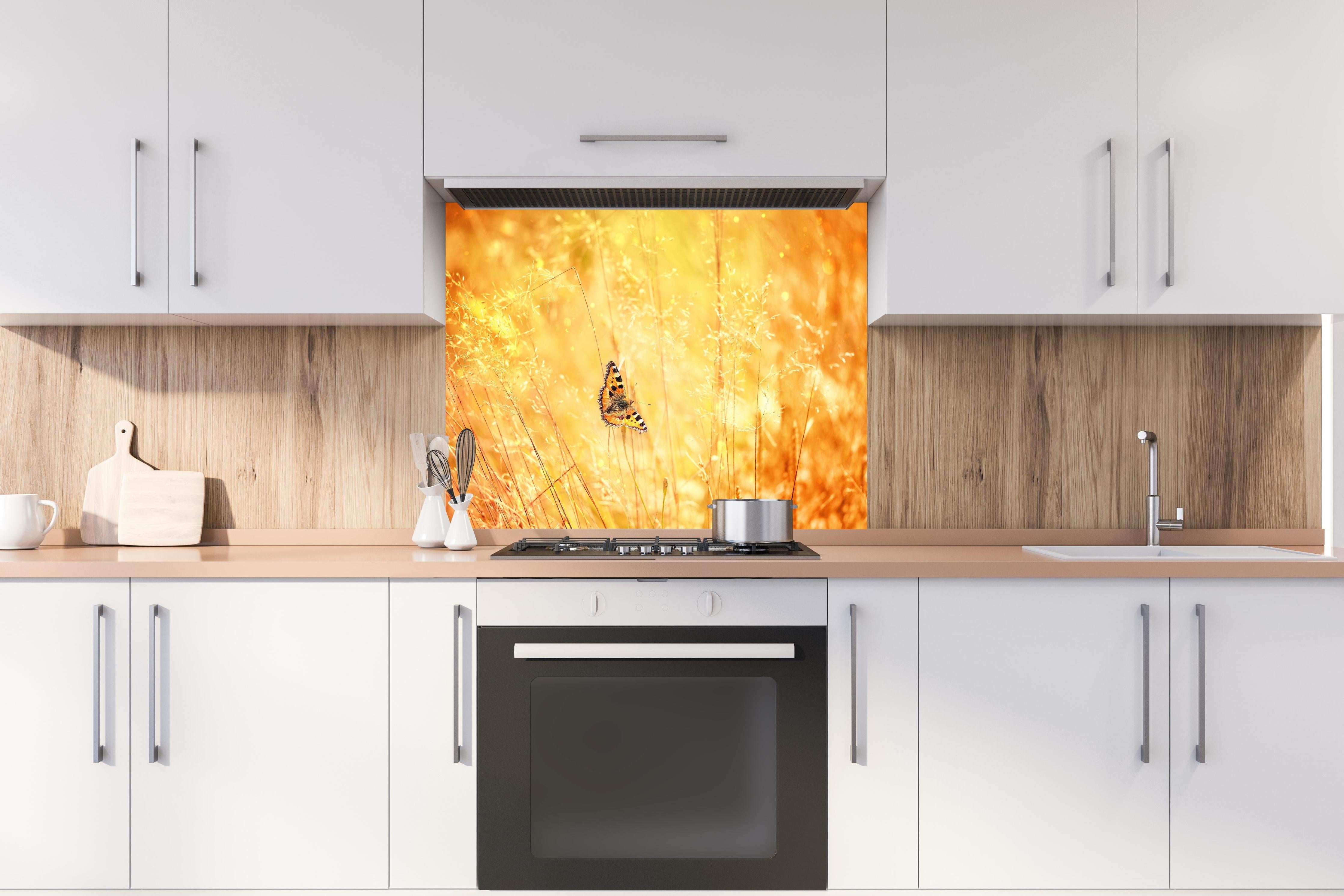 Spritzschutz - Warme Goldtöne im sommerlichen Feldmotiv hinter einem Cerankochfeld zwischen Holz-Kochutensilien
