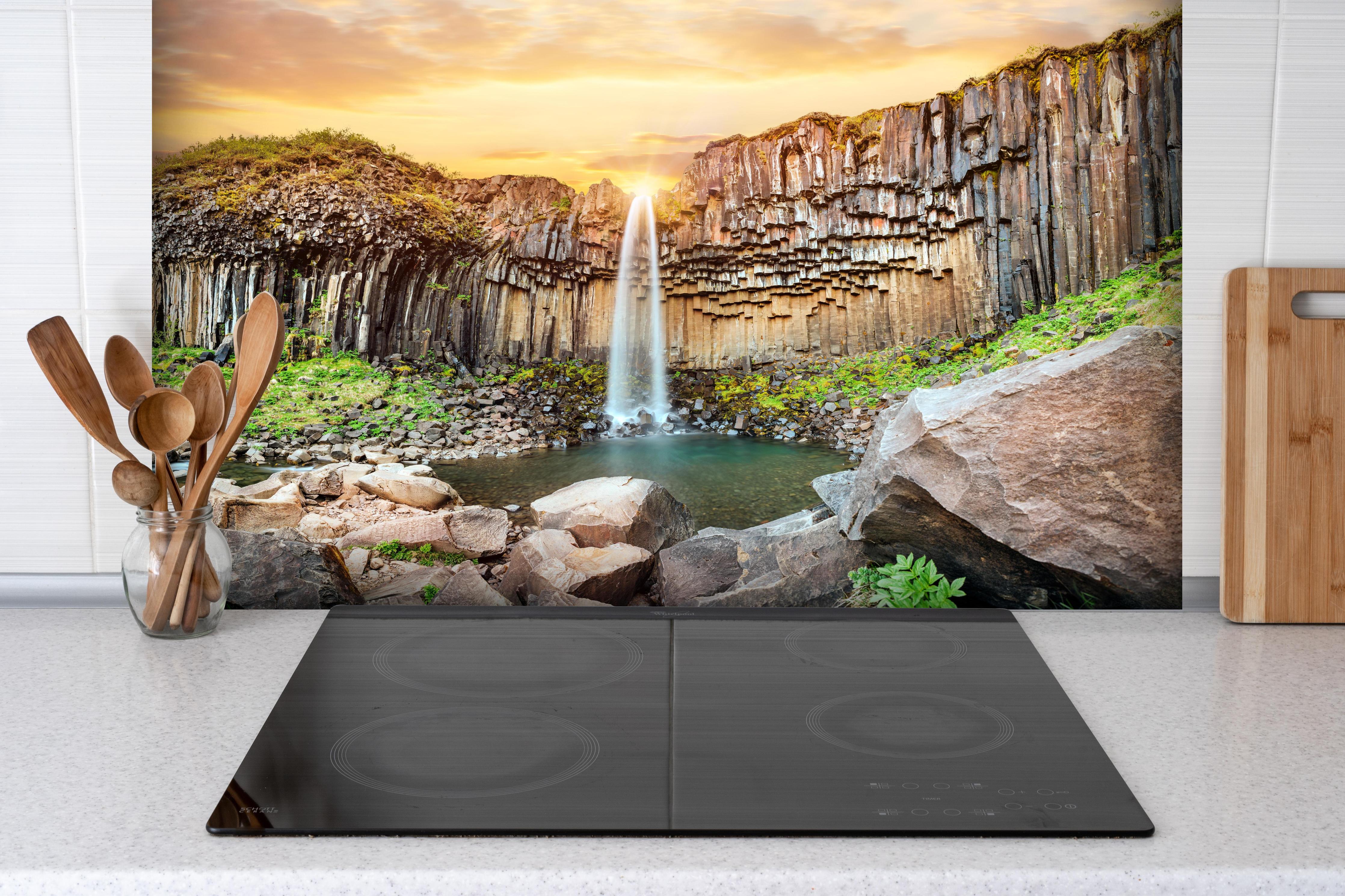 Spritzschutz - Wasserfall "Svartifoss" im Skaftafell-Nationalpark hinter einem Cerankochfeld zwischen Holz-Kochutensilien
