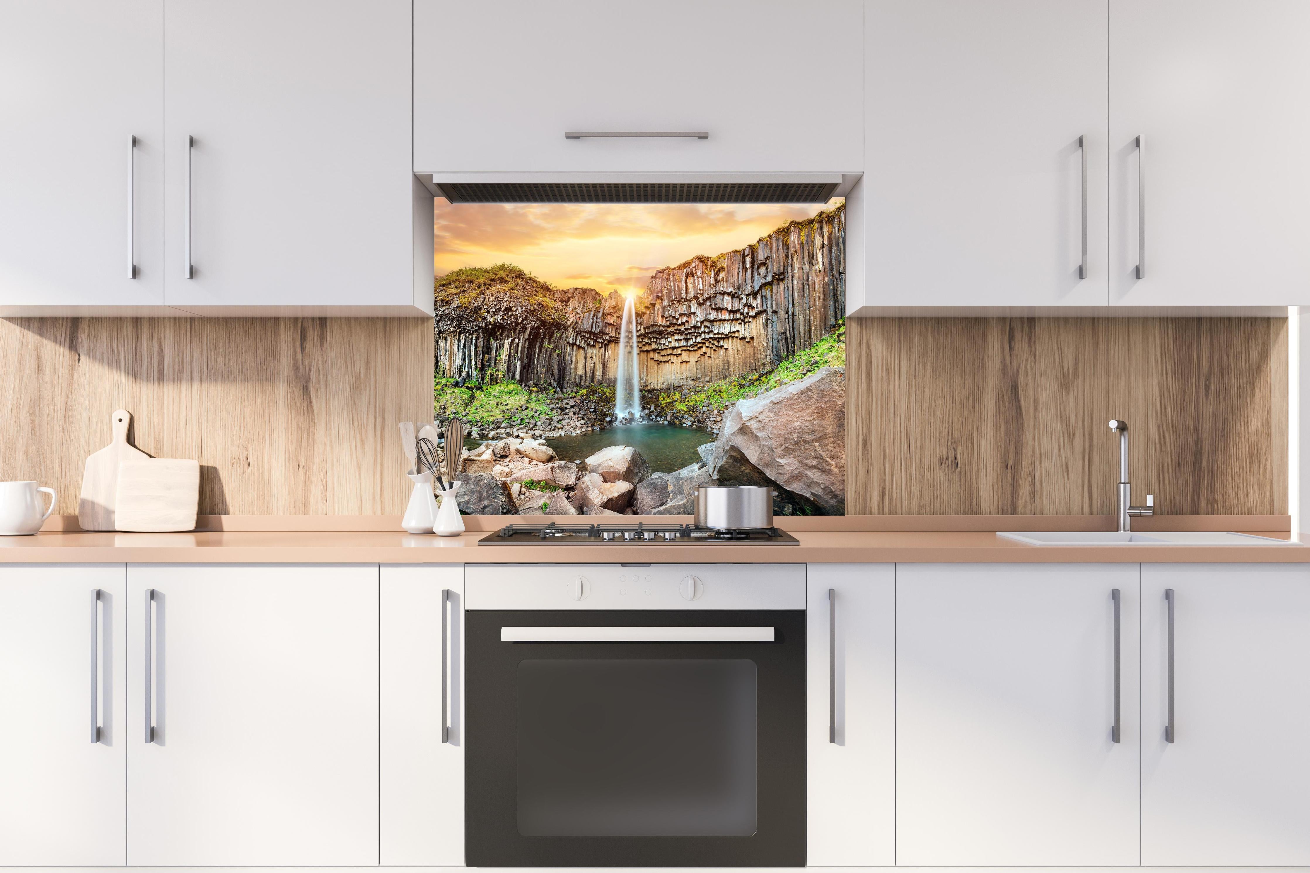 Spritzschutz - Wasserfall "Svartifoss" im Skaftafell-Nationalpark hinter einem Cerankochfeld zwischen Holz-Kochutensilien
