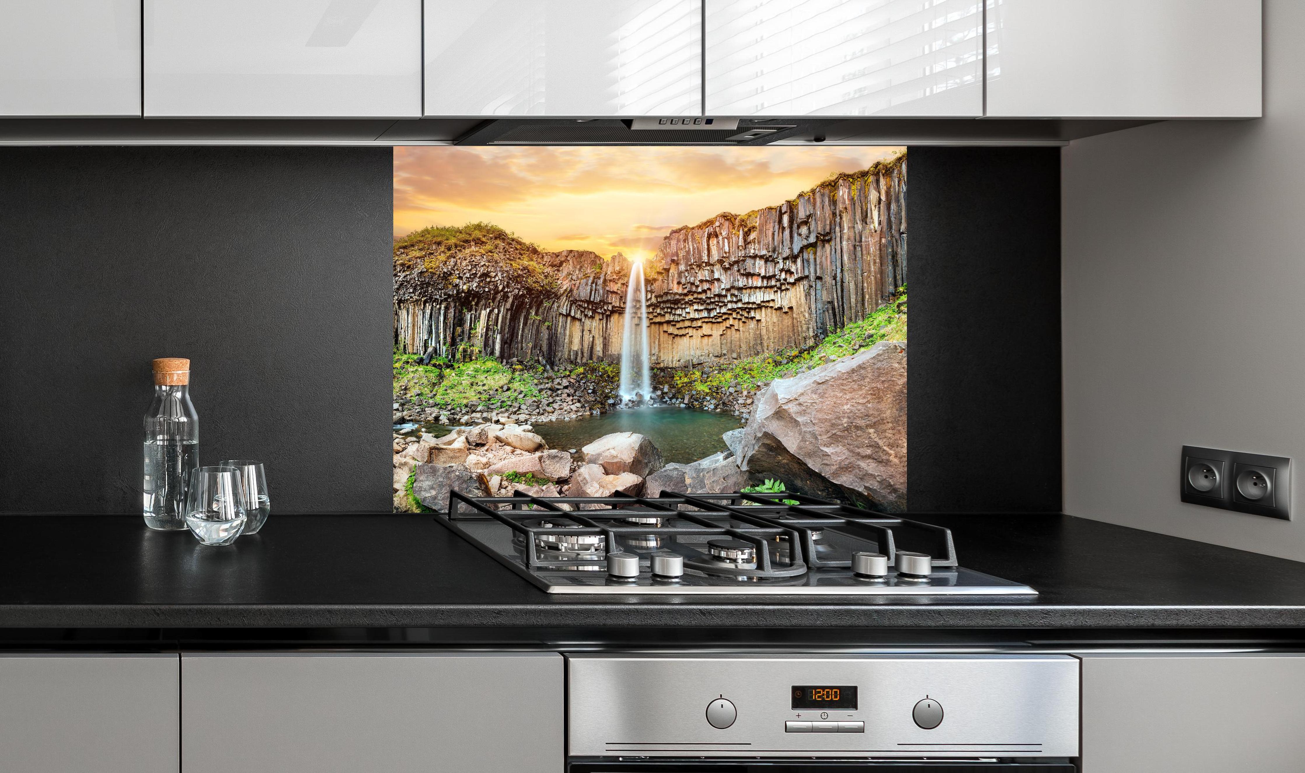 Spritzschutz - Wasserfall "Svartifoss" im Skaftafell-Nationalpark hinter einem Cerankochfeld zwischen Holz-Kochutensilien
