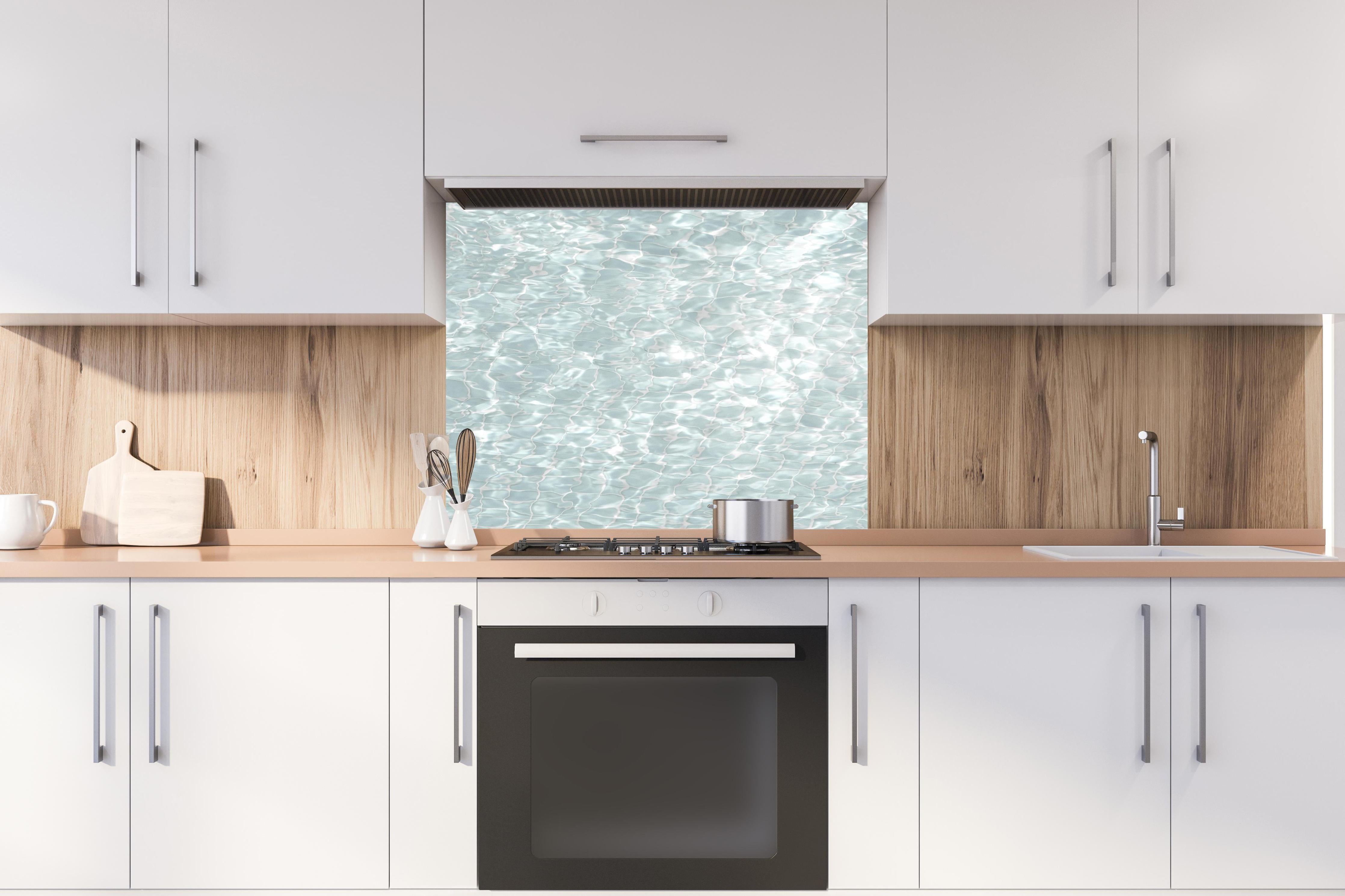 Spritzschutz - Wasseroberfläche hinter einem Cerankochfeld zwischen Holz-Kochutensilien
