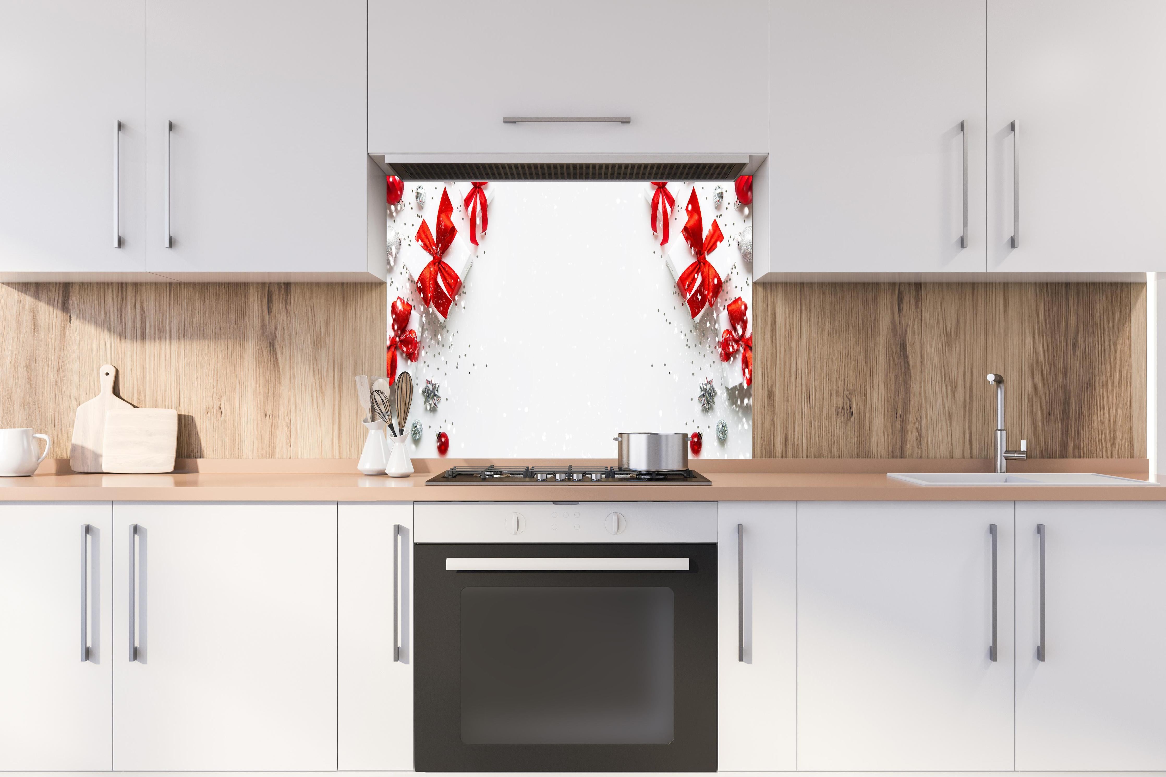 Spritzschutz - Weihnachtliche Geschenke mit Roter Schleife hinter einem Cerankochfeld zwischen Holz-Kochutensilien
