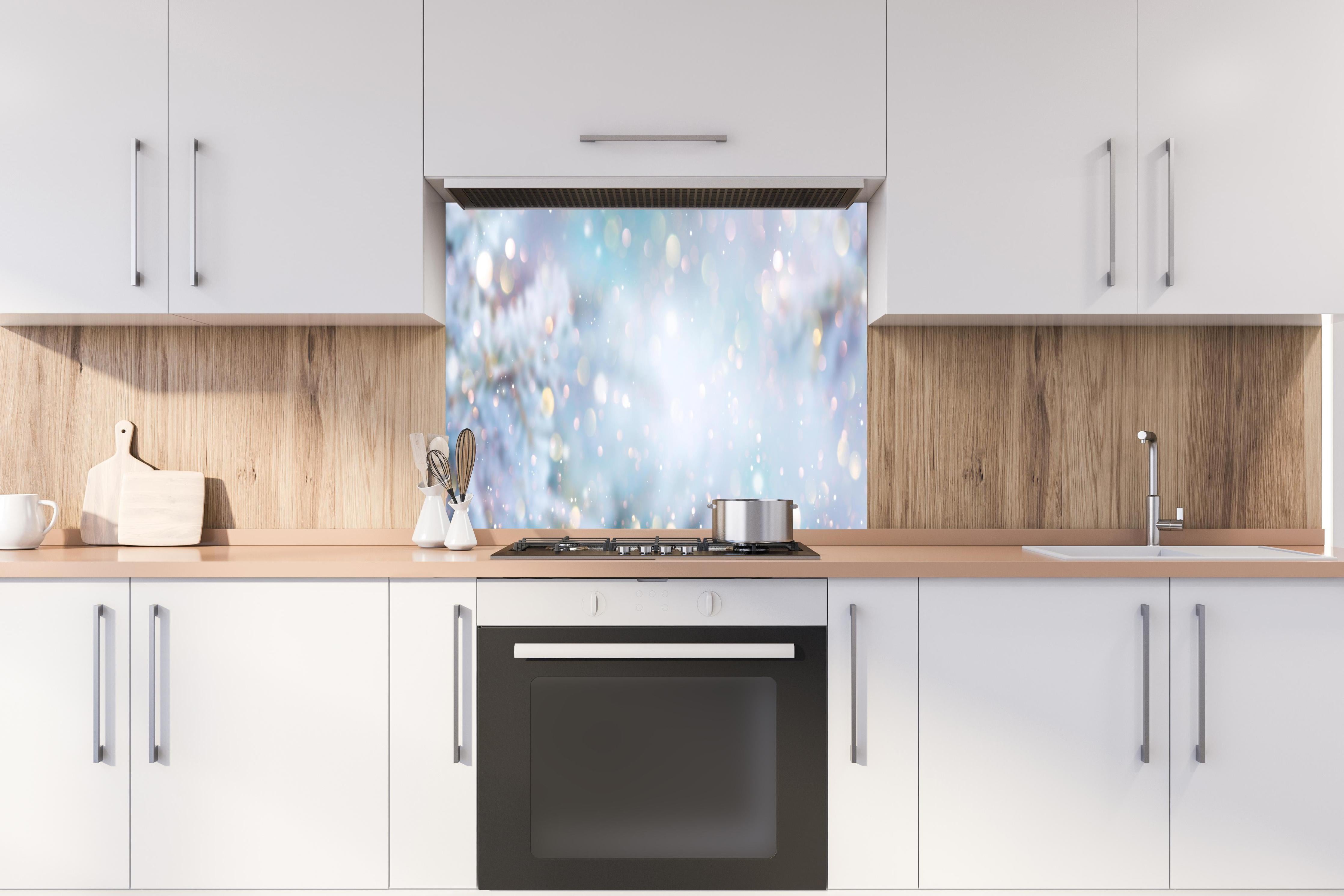 Spritzschutz - Weihnachtlicher Hintergrund mit Licht und Schnee hinter einem Cerankochfeld zwischen Holz-Kochutensilien
