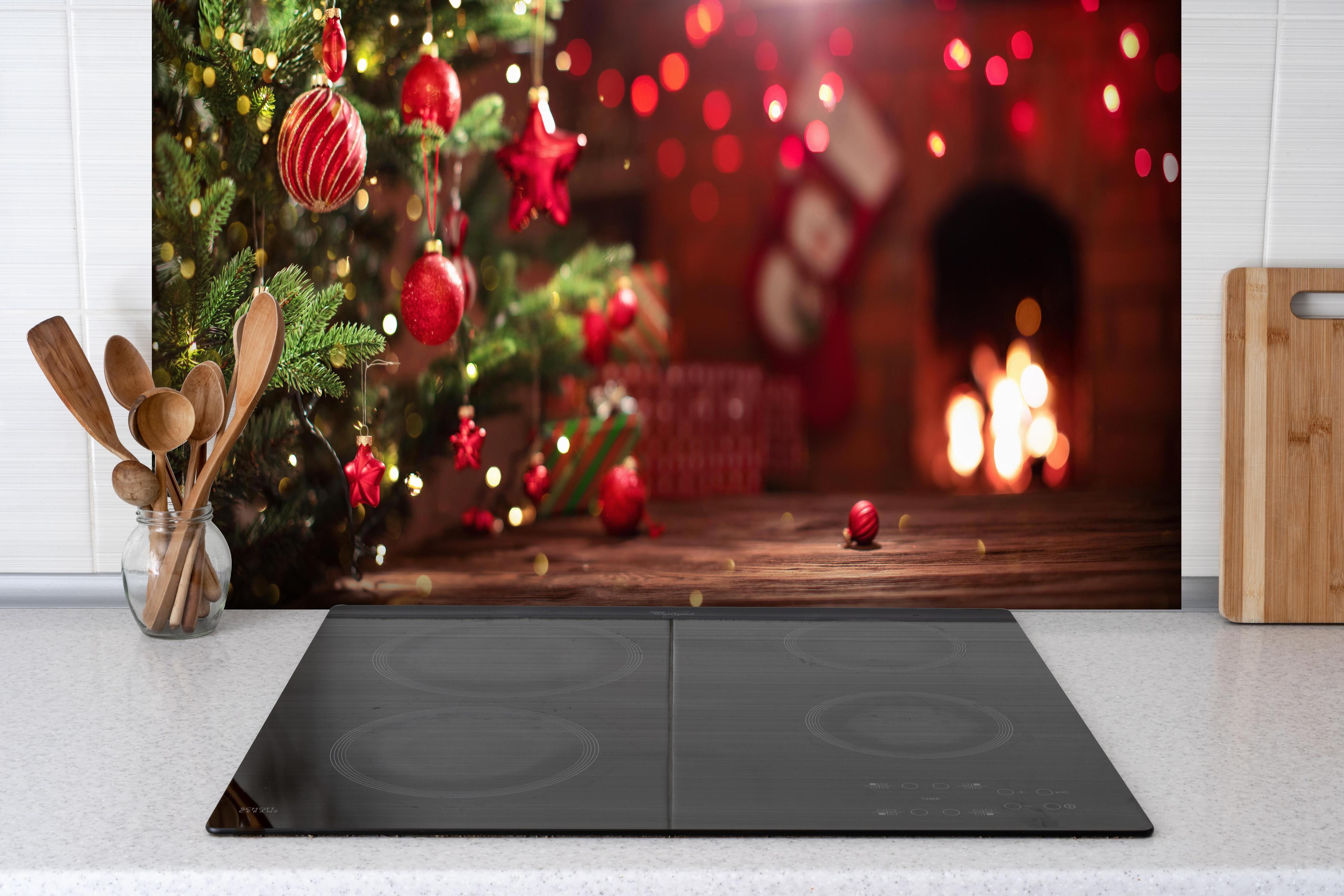 Spritzschutz - Weihnachtsbaum Rot mit Festtagsdeko hinter einem Cerankochfeld zwischen Holz-Kochutensilien
