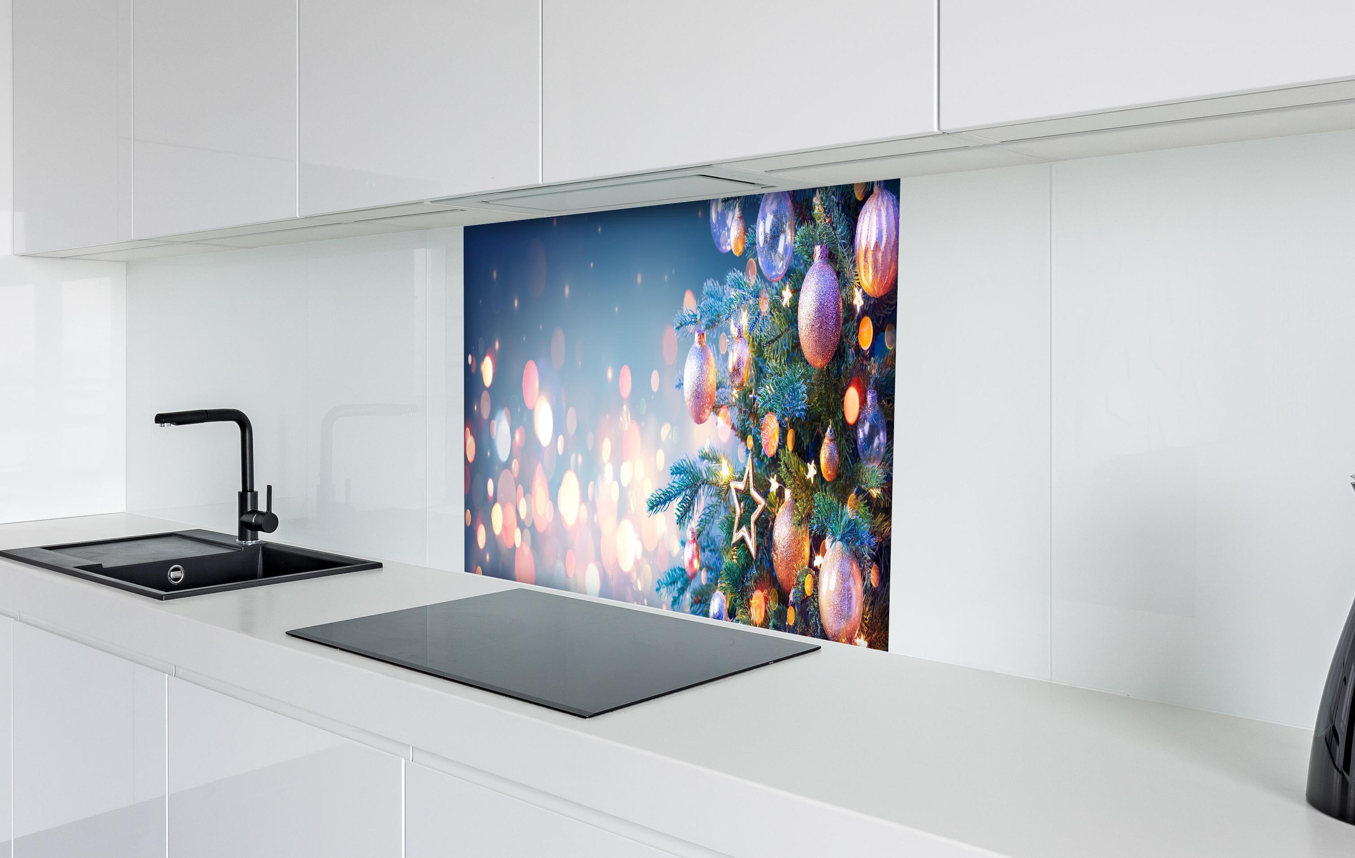 Spritzschutz - Weihnachtsbaum mit bunten Kugeln hinter einem Cerankochfeld zwischen Holz-Kochutensilien
