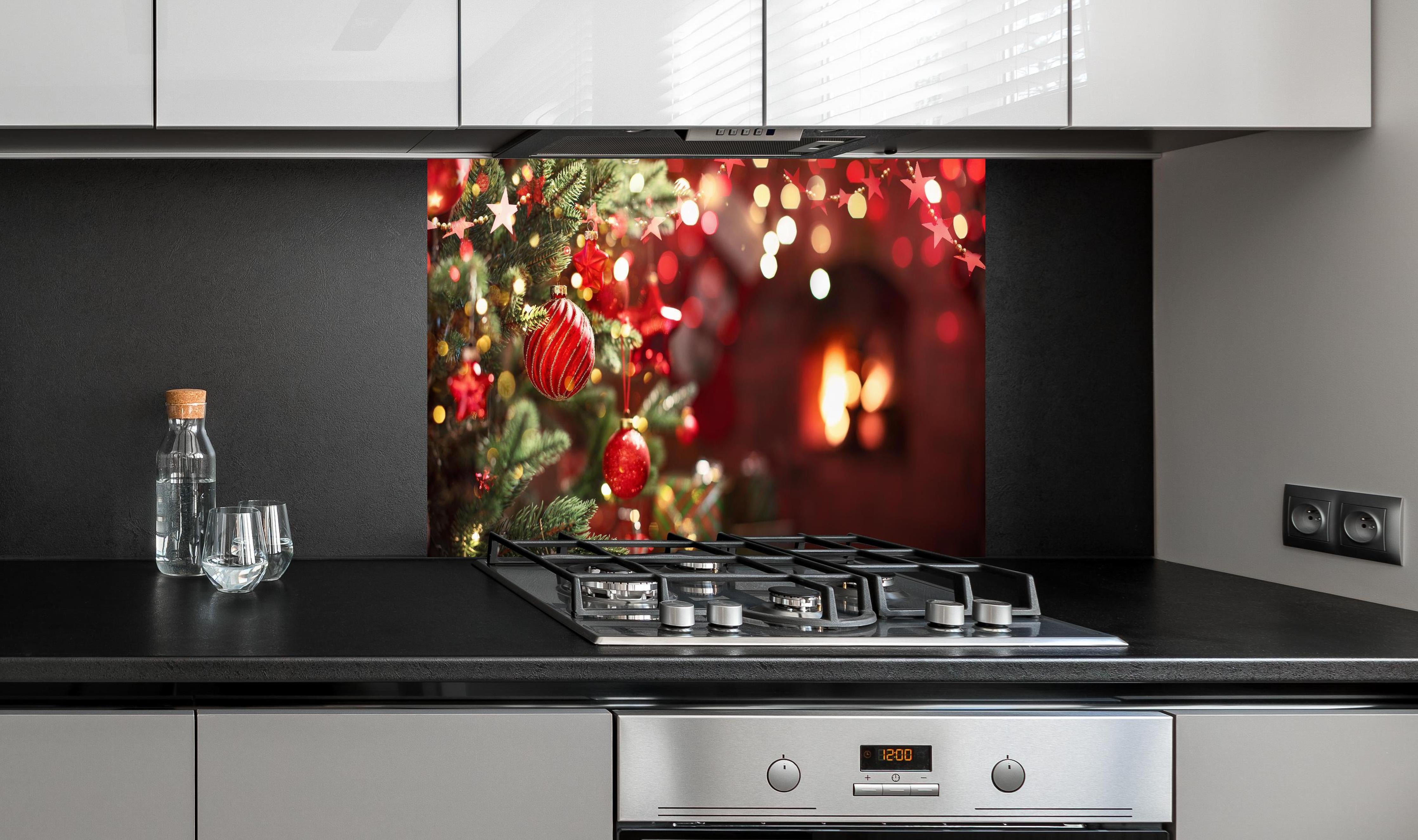 Spritzschutz - Weihnachtsbaum mit roten Kugeln und Sternen hinter einem Cerankochfeld zwischen Holz-Kochutensilien
