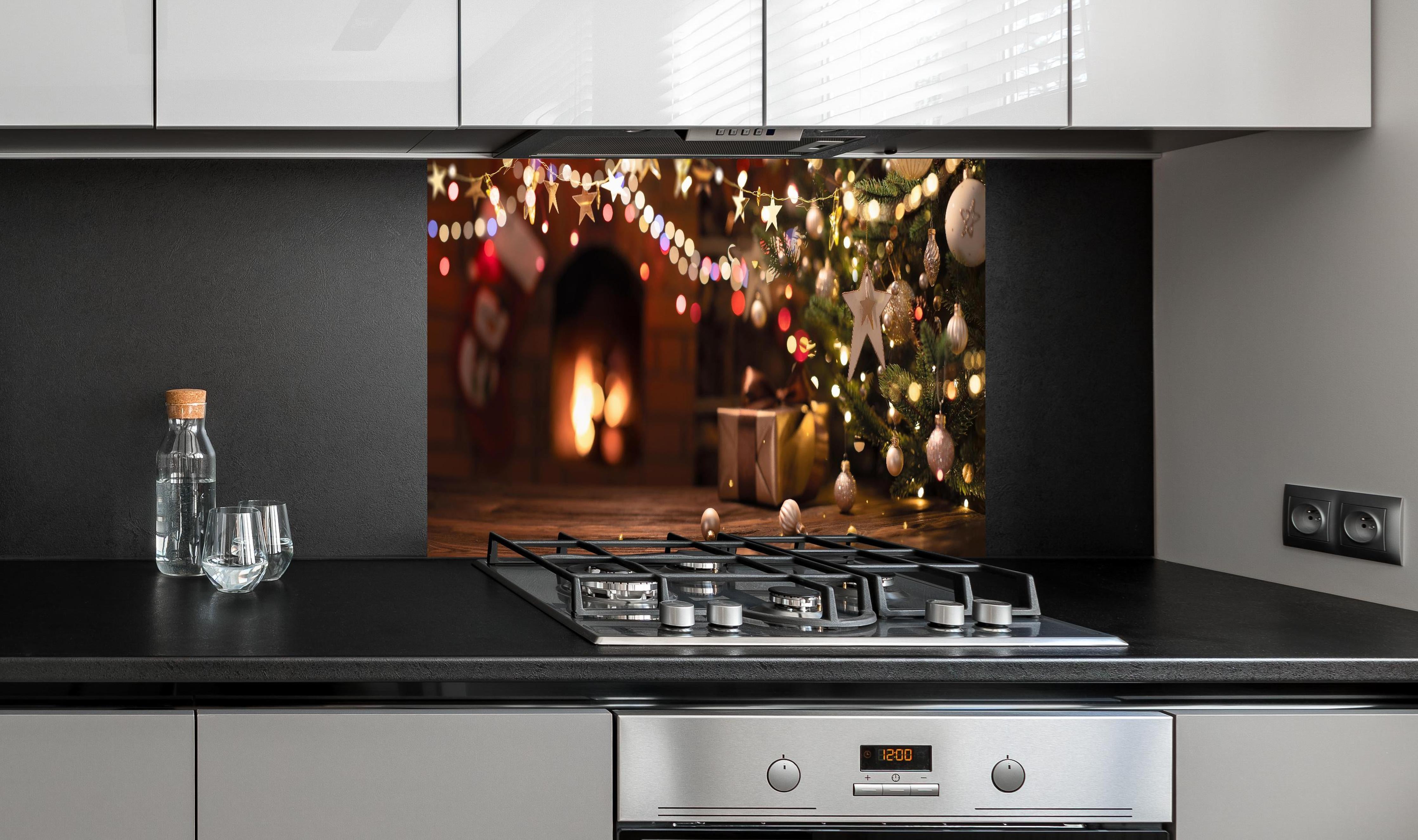 Spritzschutz - Weihnachtsbaum, Sterne und festliche Lichter hinter einem Cerankochfeld zwischen Holz-Kochutensilien
