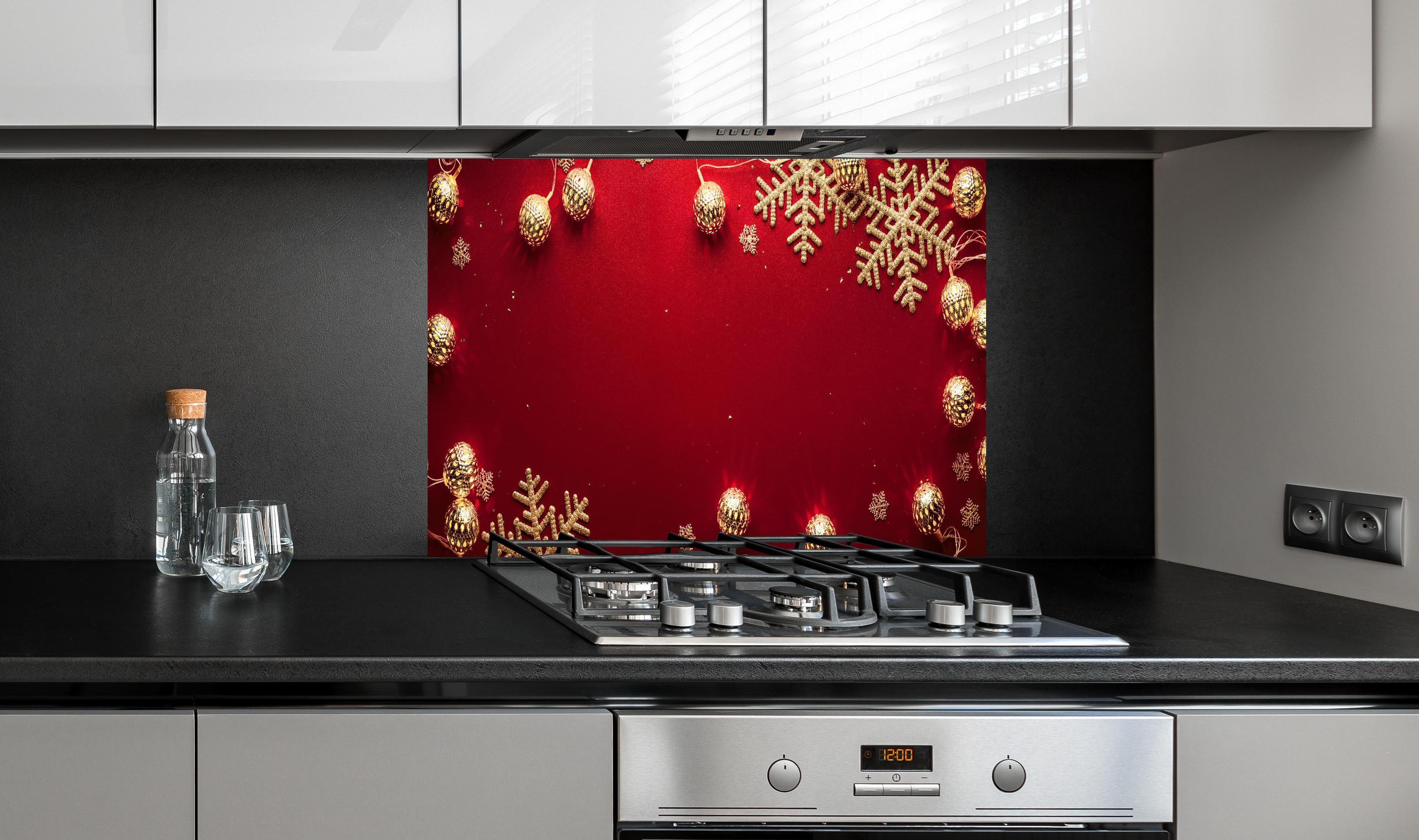 Spritzschutz - Weihnachtsdekoration auf rotem Hintergrund hinter einem Cerankochfeld zwischen Holz-Kochutensilien
