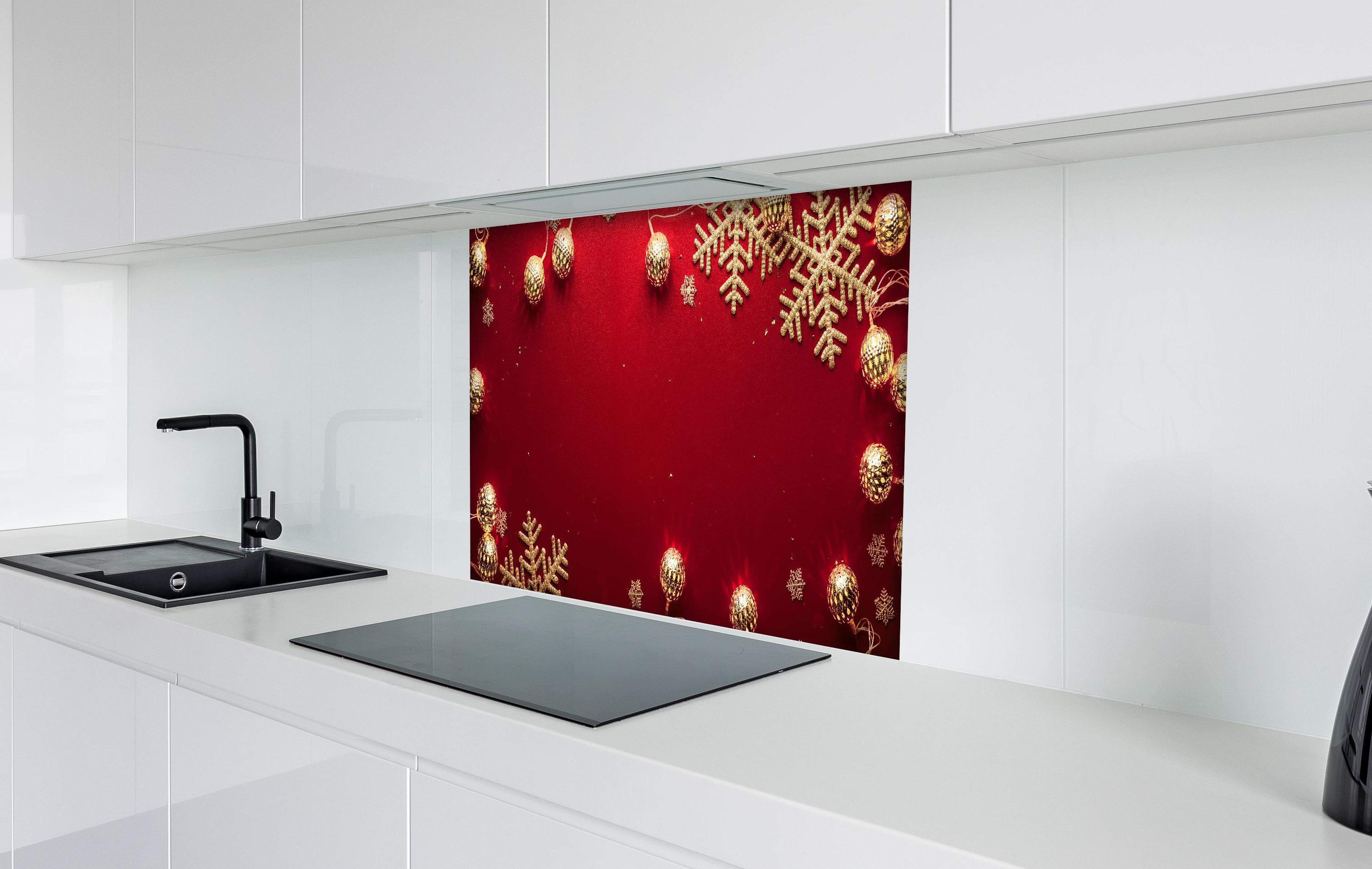 Spritzschutz - Weihnachtsdekoration auf rotem Hintergrund hinter einem Cerankochfeld zwischen Holz-Kochutensilien
