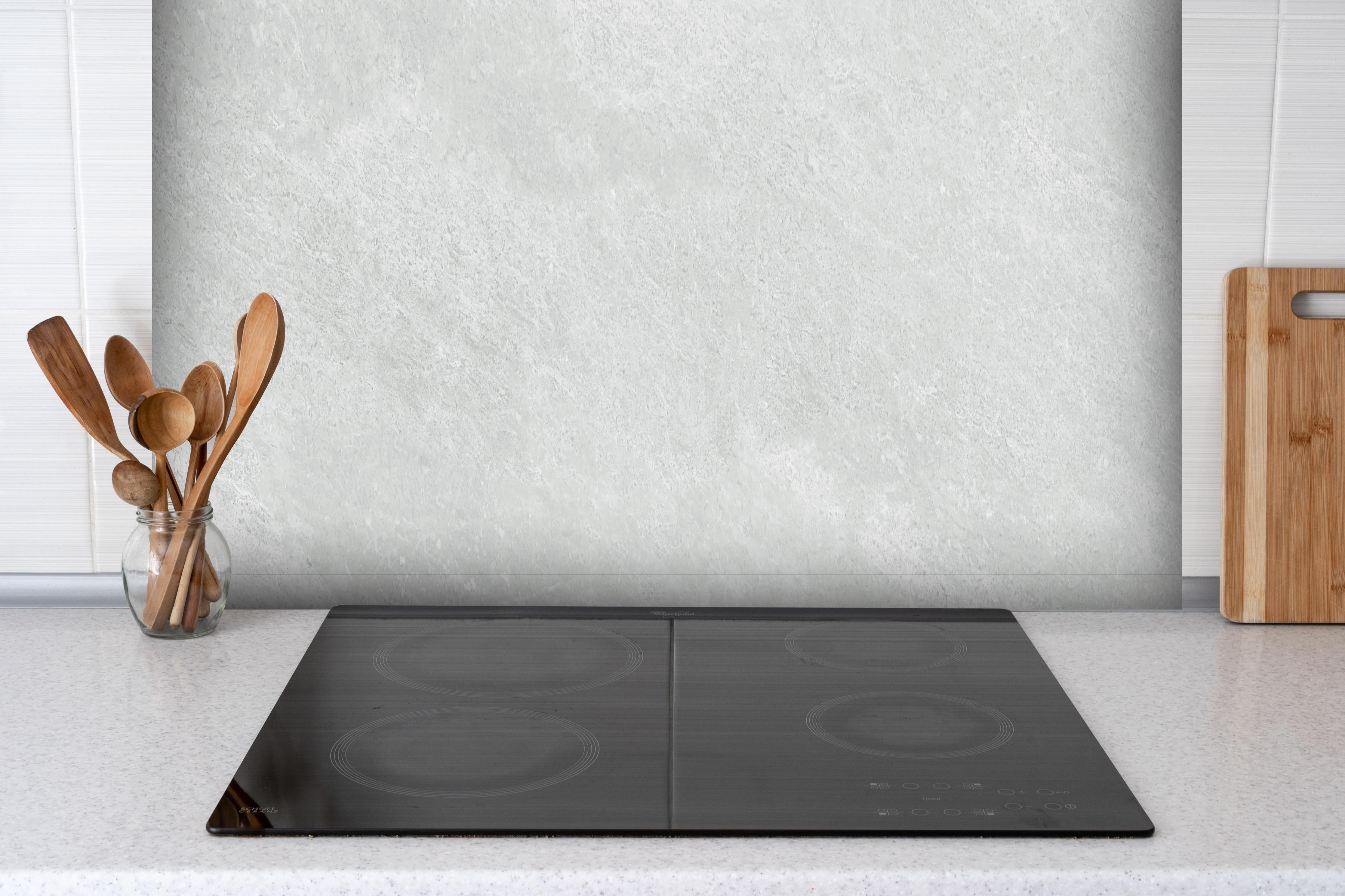 Spritzschutz - Weiße Licht Marmor Textur hinter einem Cerankochfeld zwischen Holz-Kochutensilien
