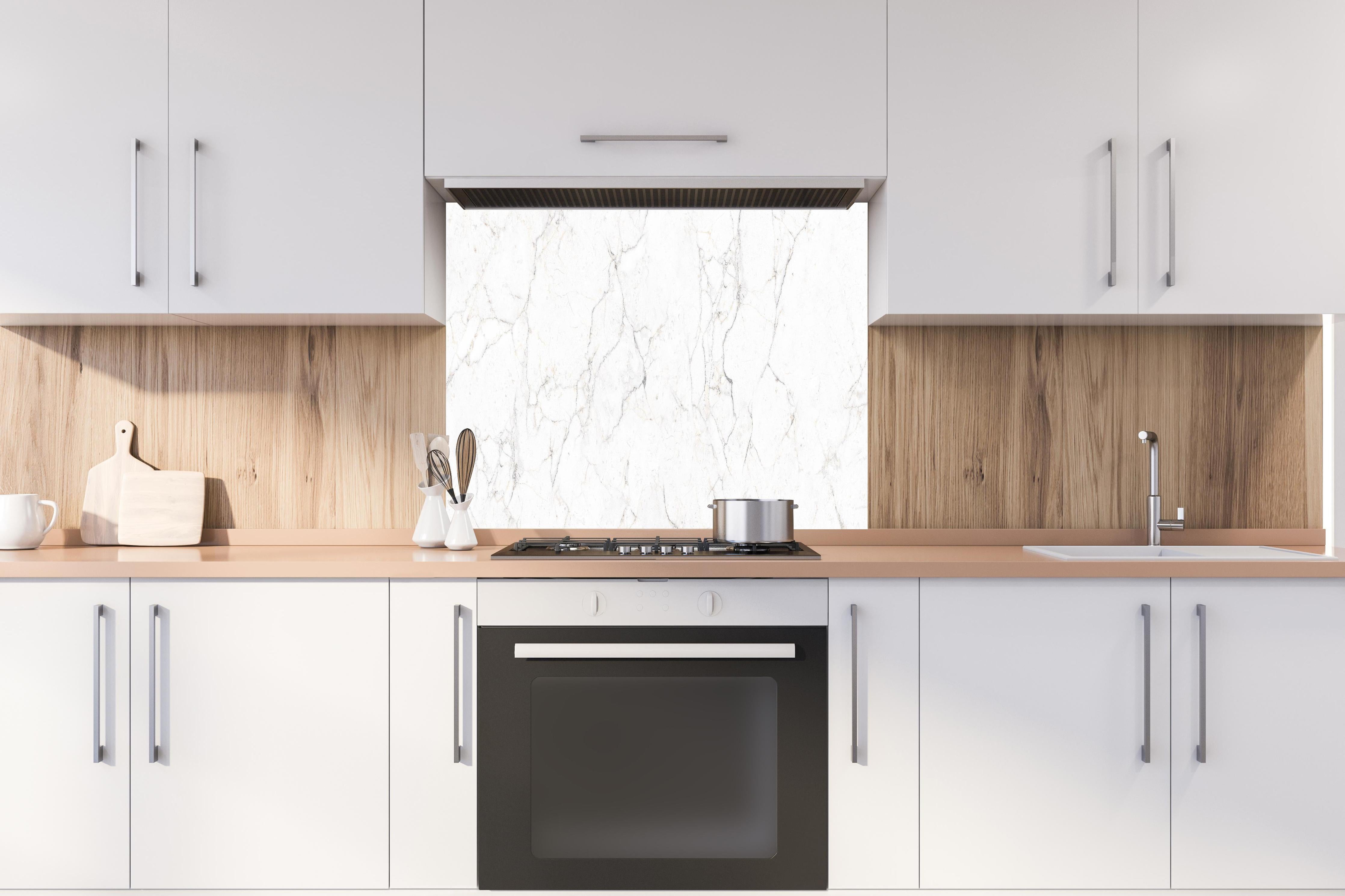 Spritzschutz - Weiße Marmor - Beton Textur hinter einem Cerankochfeld zwischen Holz-Kochutensilien
