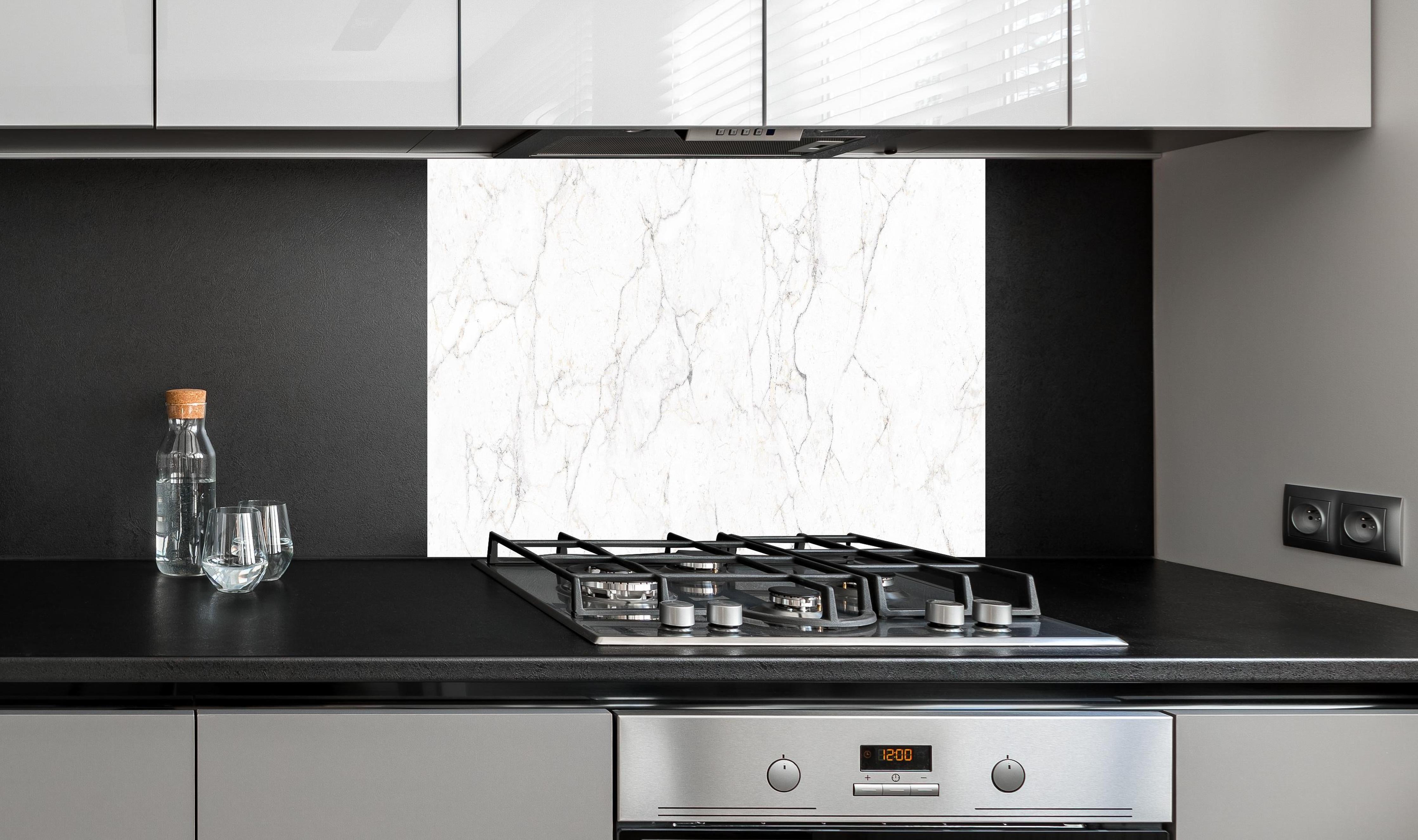 Spritzschutz - Weiße Marmor - Beton Textur hinter einem Cerankochfeld zwischen Holz-Kochutensilien
