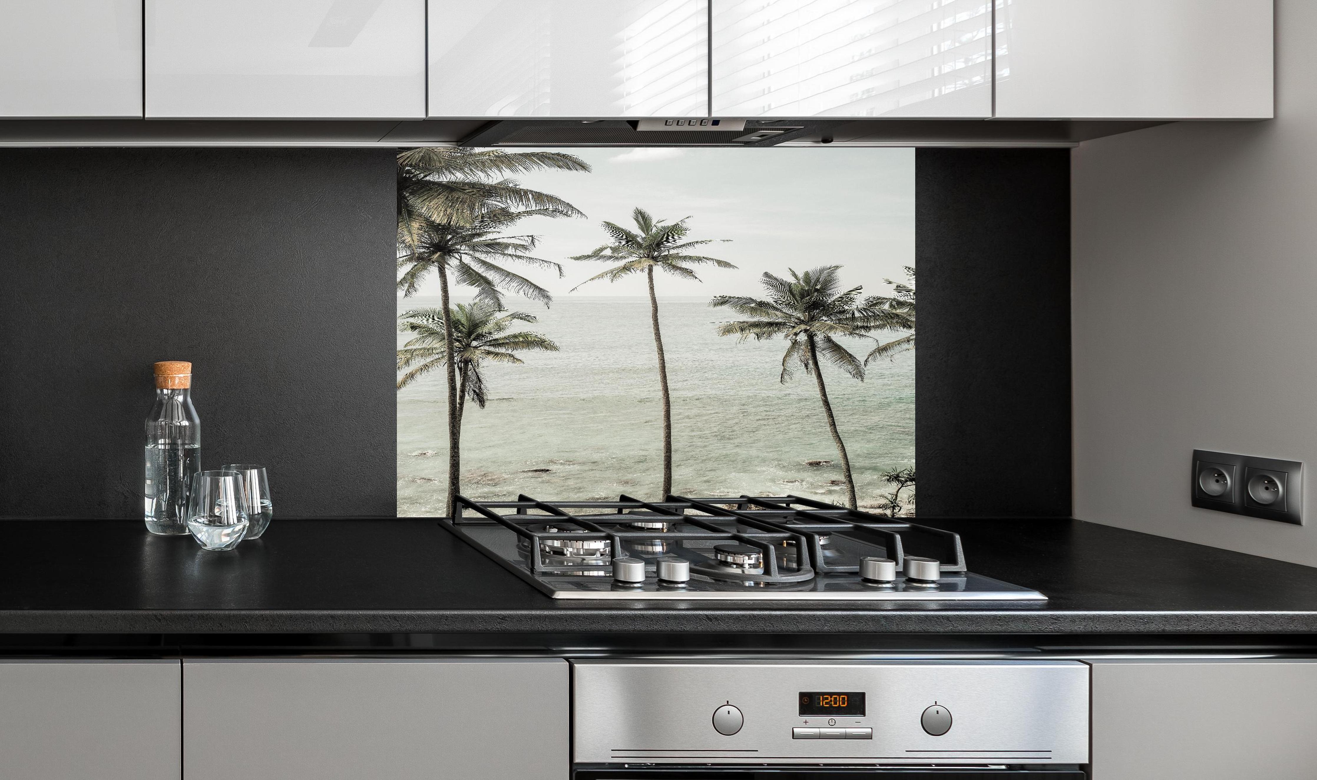 Spritzschutz - Weiße Sandstrände mit grünen Palmen hinter einem Cerankochfeld zwischen Holz-Kochutensilien
