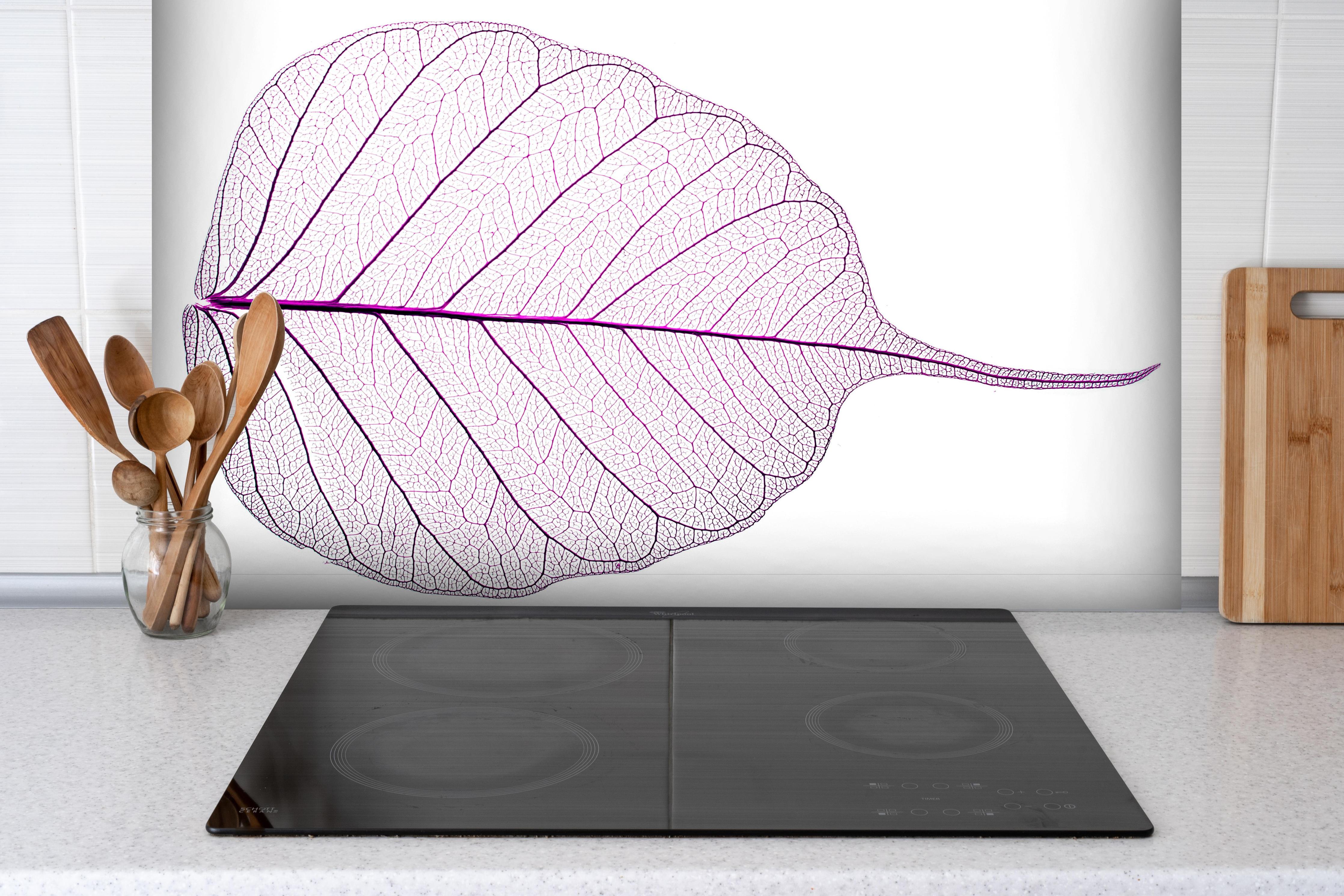 Spritzschutz - Weißes Blatt Skelett mit lila Akzent hinter einem Cerankochfeld zwischen Holz-Kochutensilien
