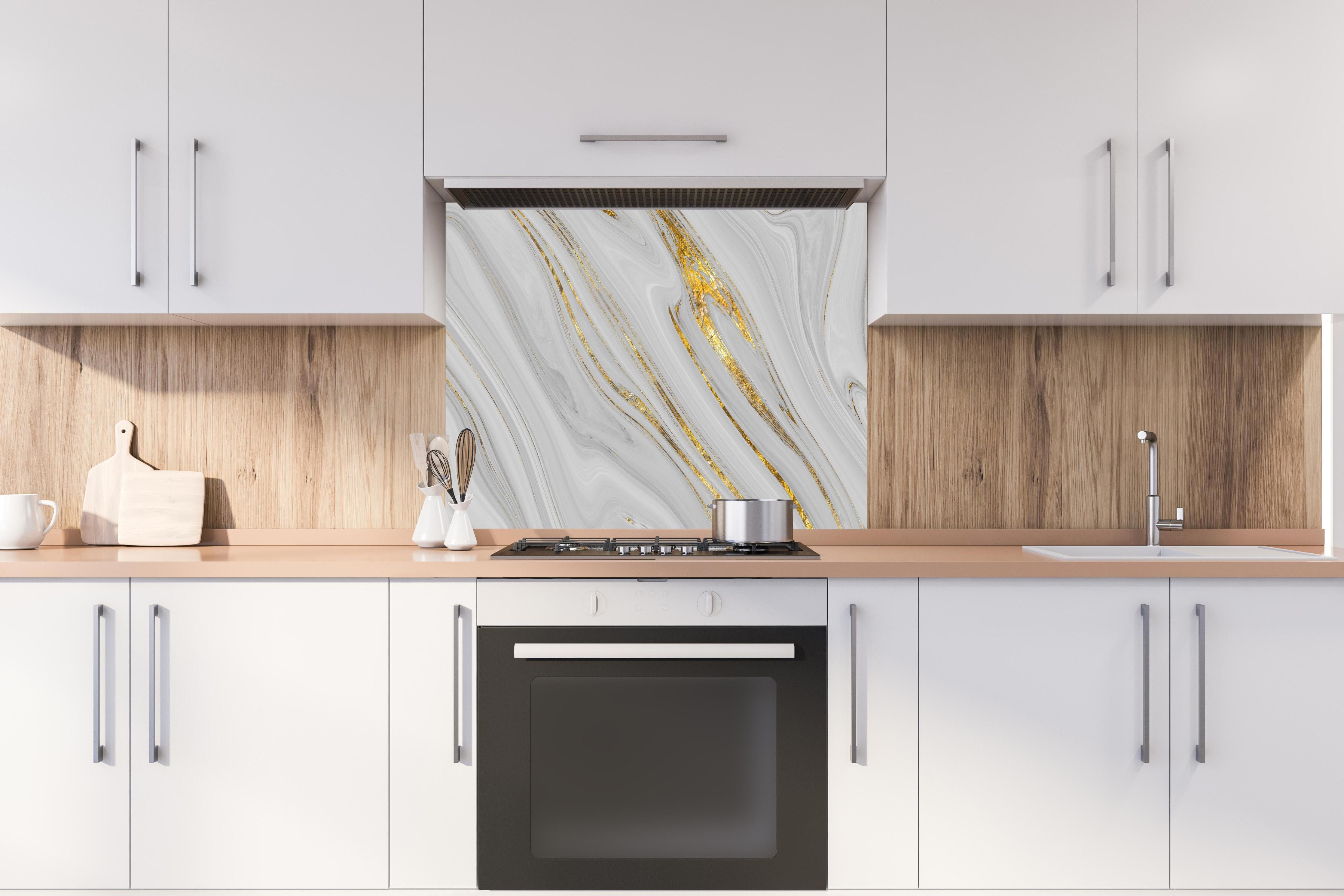Spritzschutz - Weißes Marmor Muster mit goldenen Adern hinter einem Cerankochfeld zwischen Holz-Kochutensilien
