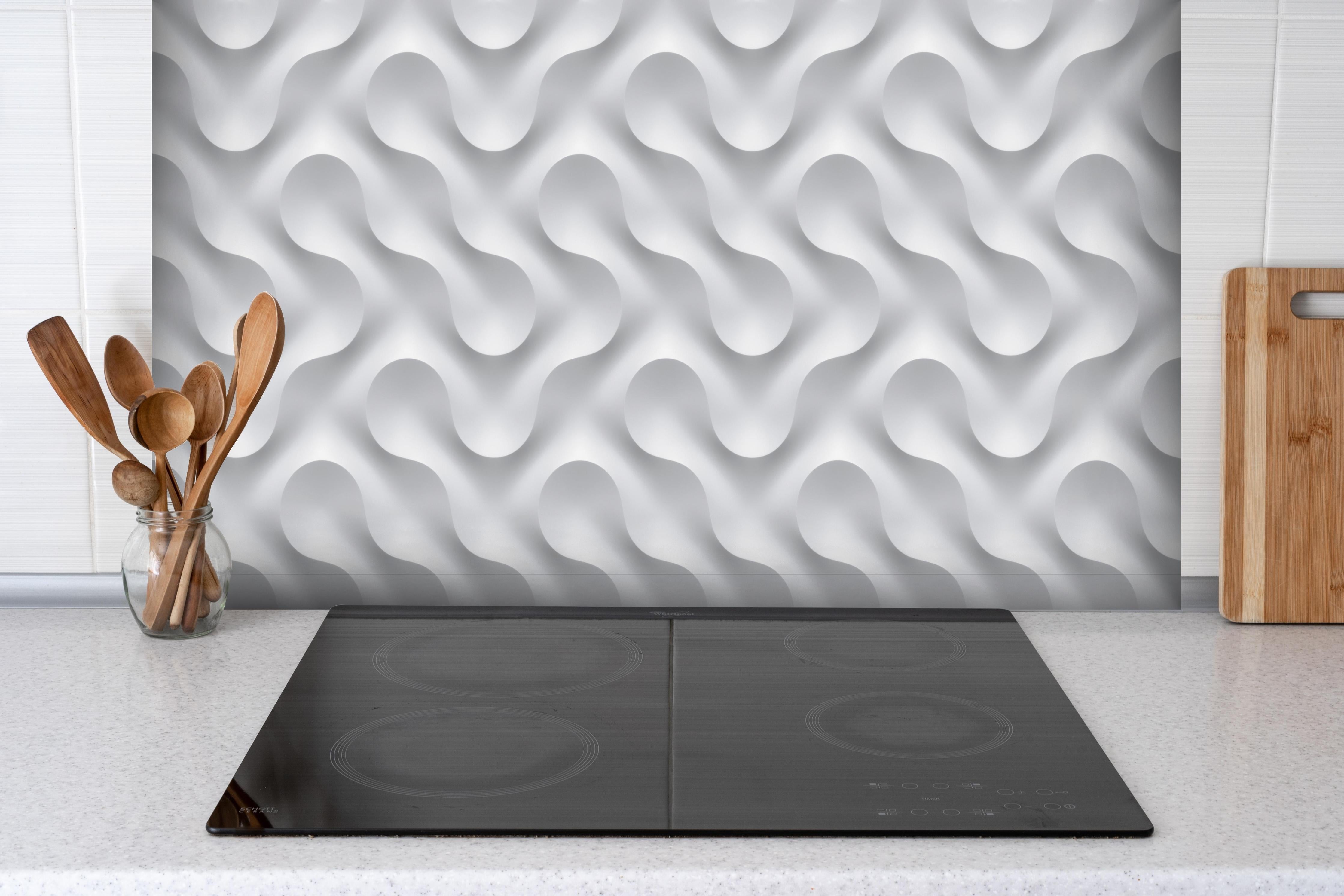 Spritzschutz - Weißes Wellen Muster hinter einem Cerankochfeld zwischen Holz-Kochutensilien
