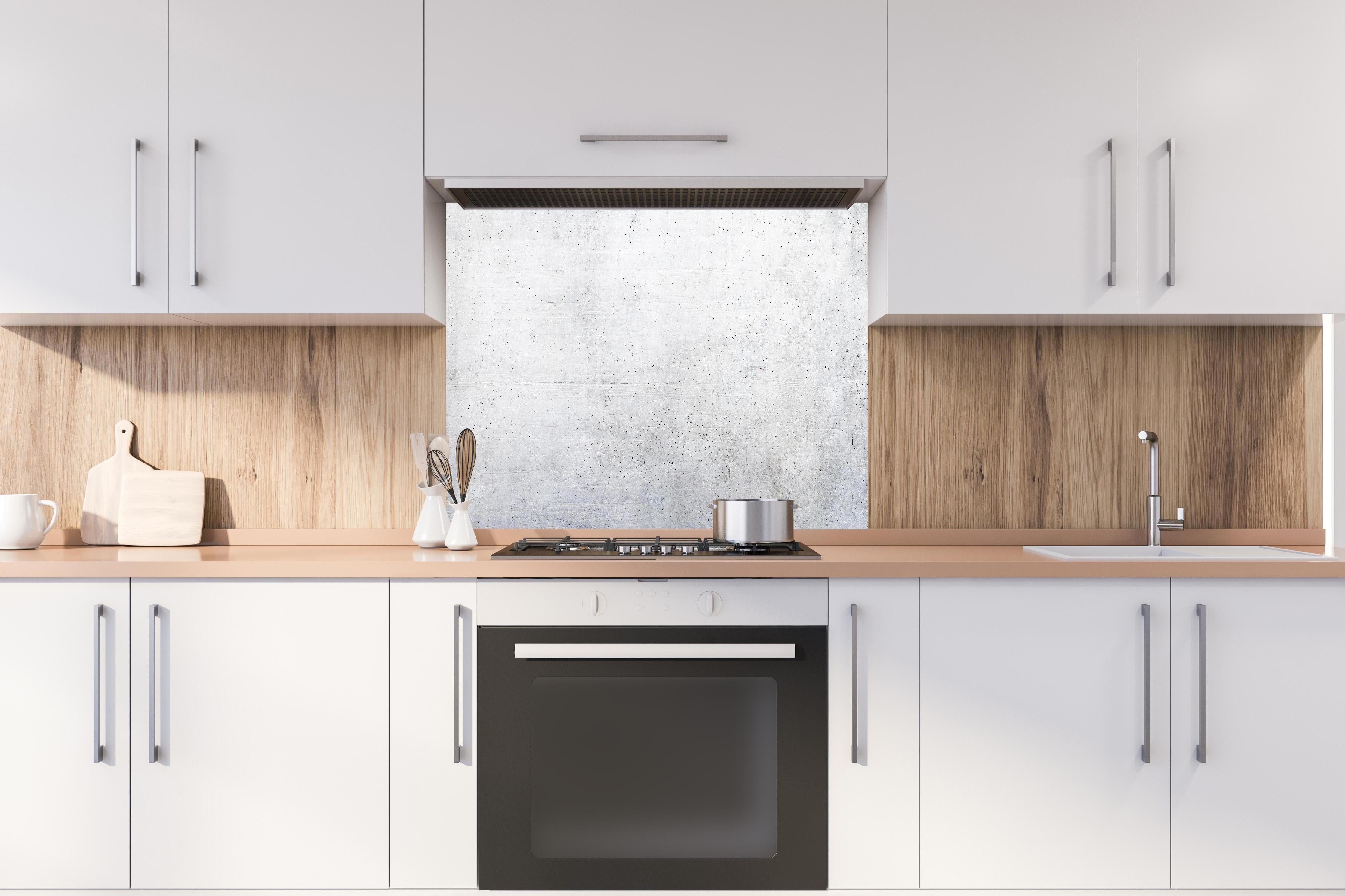 Spritzschutz - Weißes Zement Design hinter einem Cerankochfeld zwischen Holz-Kochutensilien
