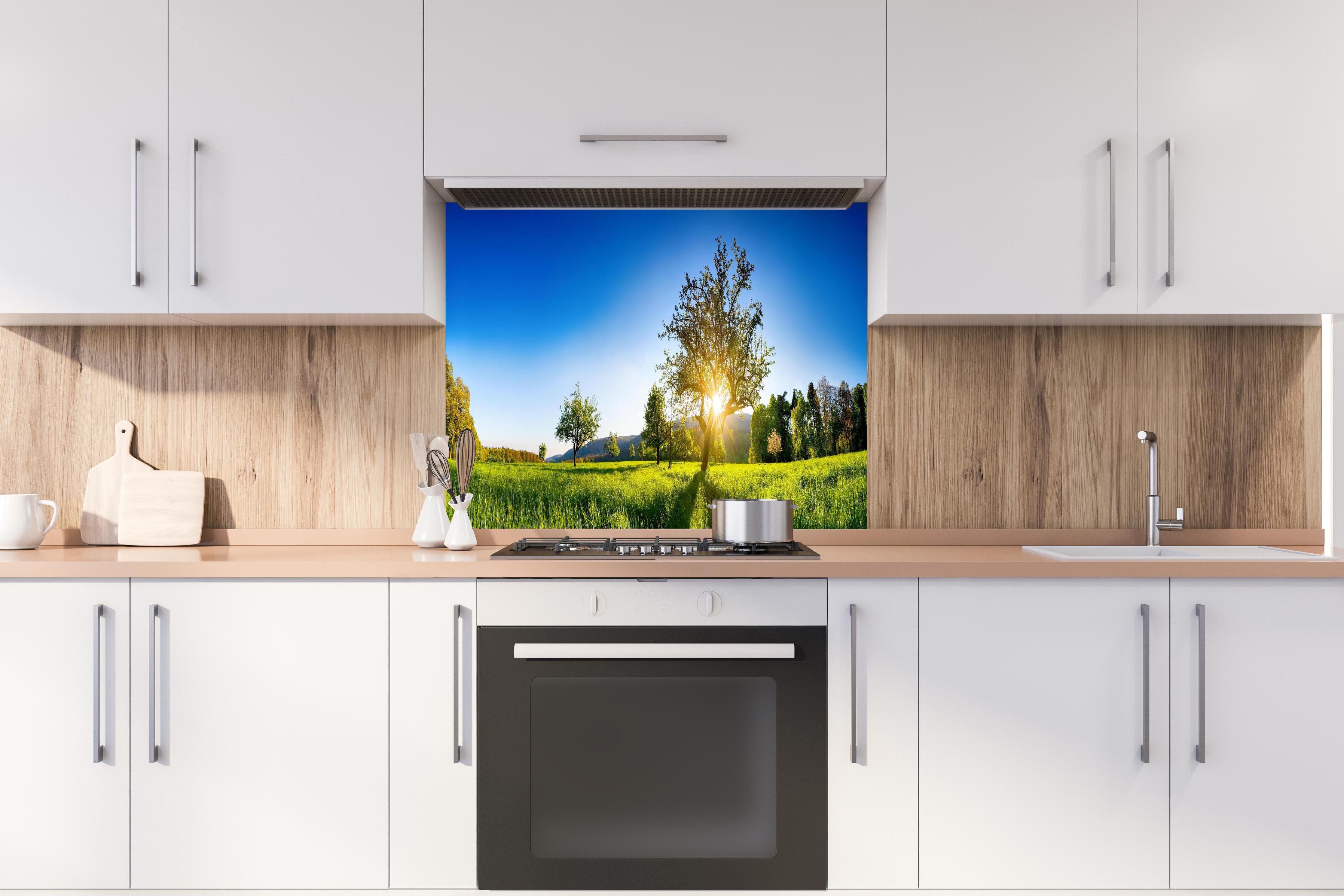 Spritzschutz - Weite Landschaft unter klarem blauem Himmel hinter einem Cerankochfeld zwischen Holz-Kochutensilien
