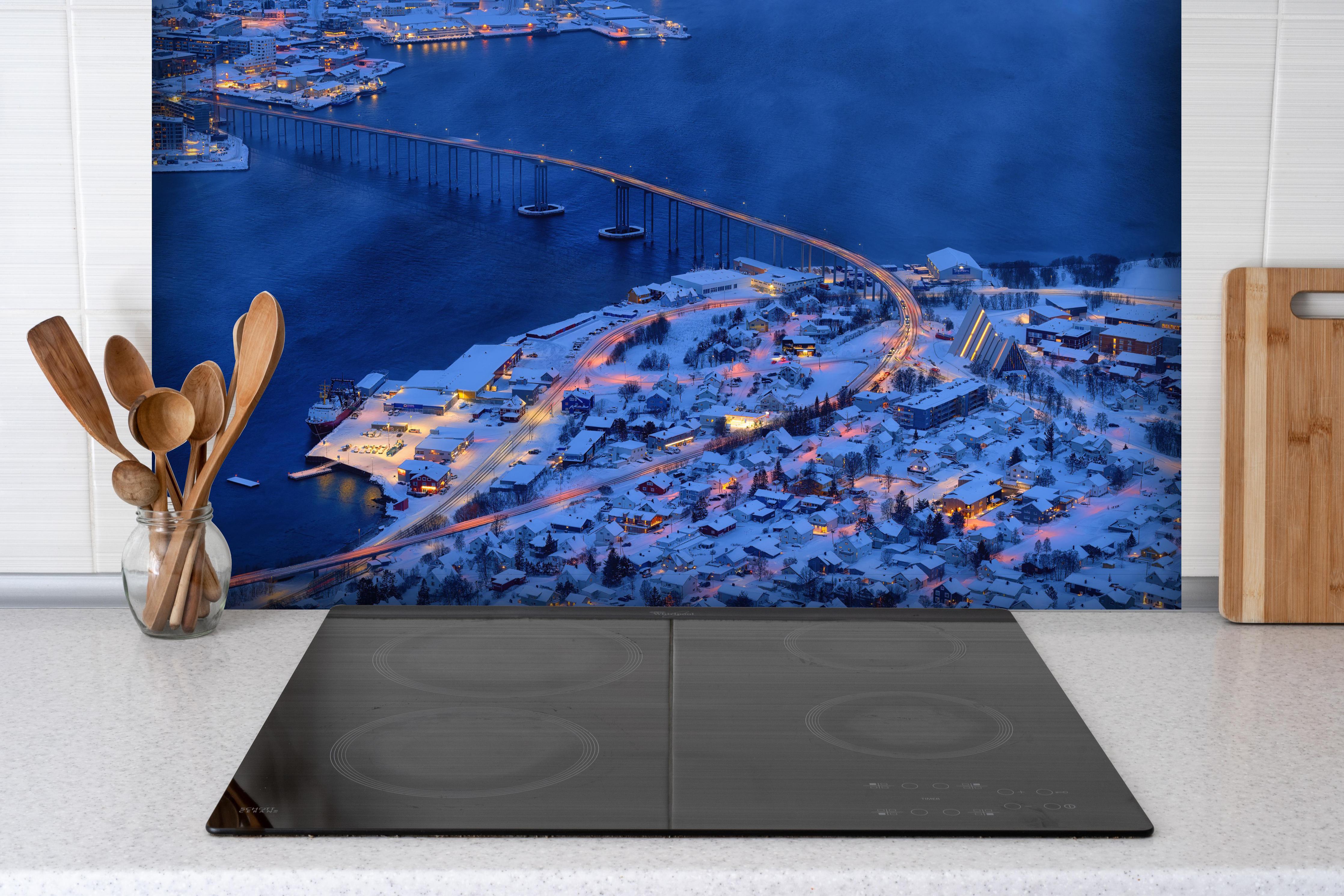 Spritzschutz - Winterliche Abendbrücke in Tromsø, Norwegen hinter einem Cerankochfeld zwischen Holz-Kochutensilien
