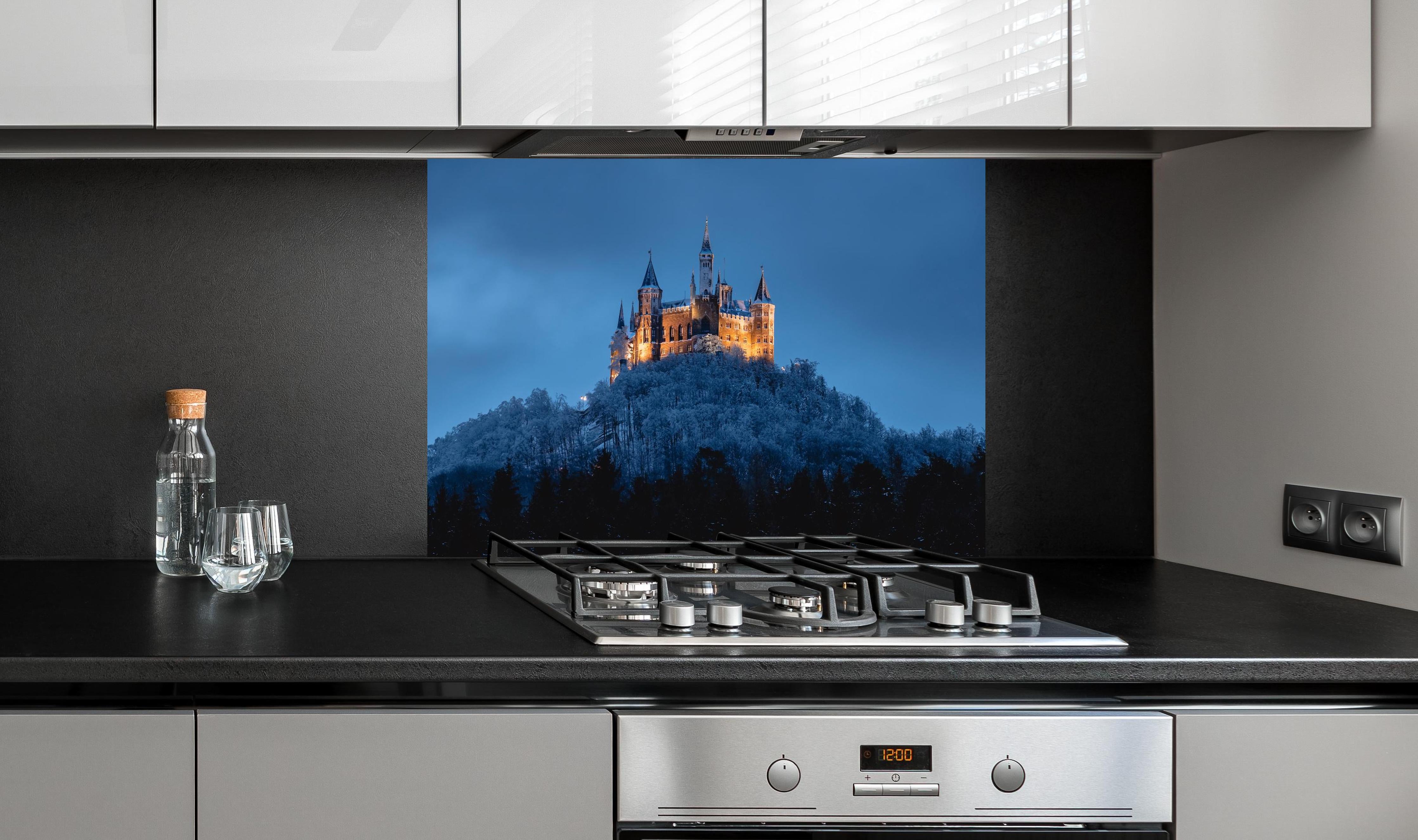 Spritzschutz - Winterliche Atmosphäre - Burg von Hohenzollern hinter einem Cerankochfeld zwischen Holz-Kochutensilien
