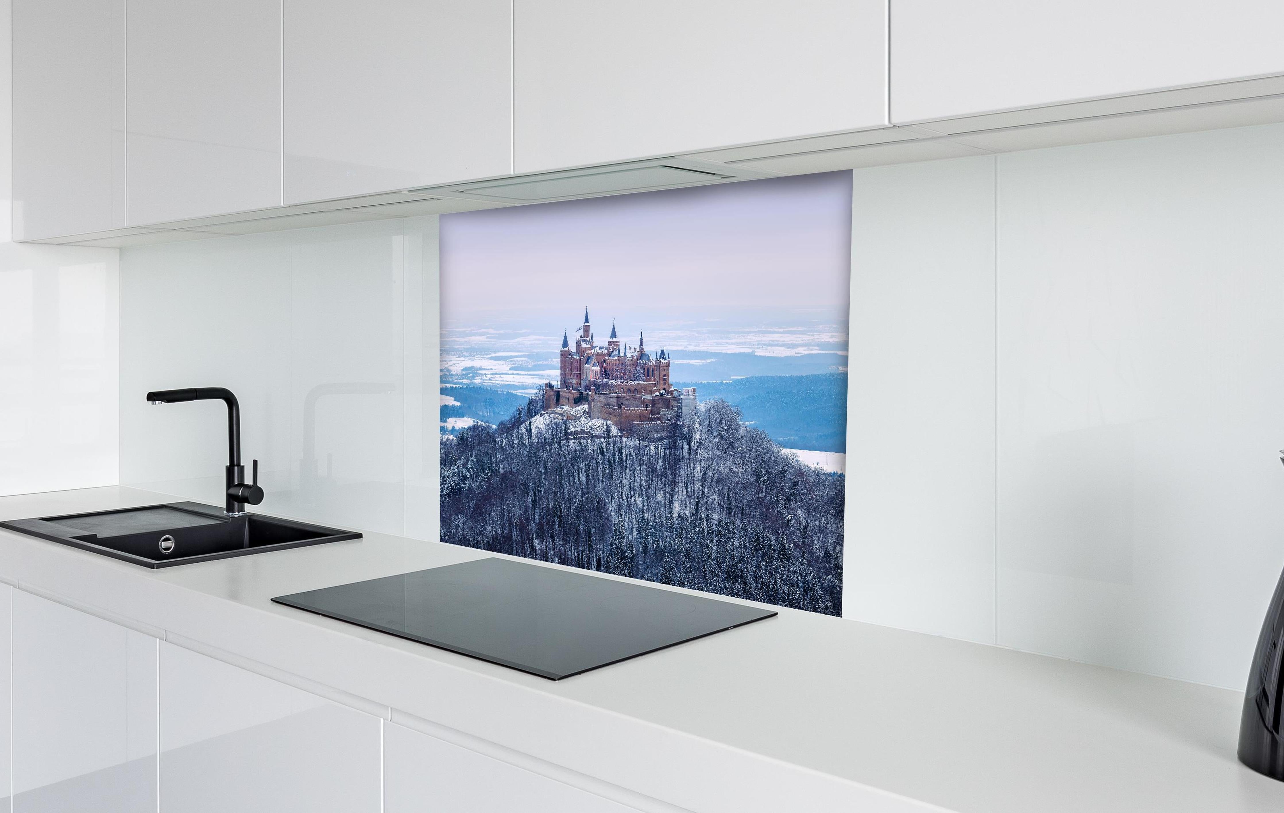 Spritzschutz - Winterliche Burg von Hohenzollern hinter einem Cerankochfeld zwischen Holz-Kochutensilien
