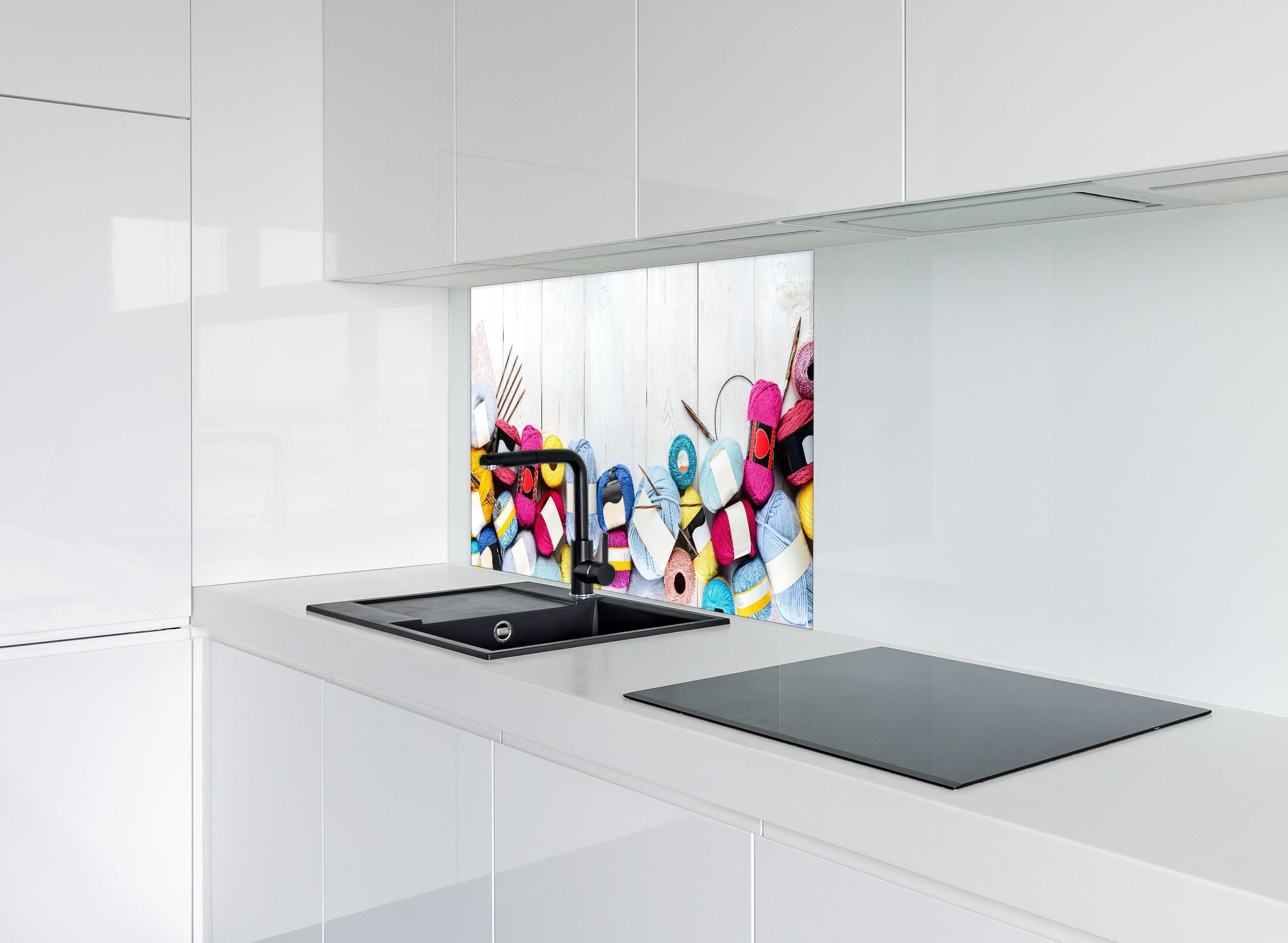 Spritzschutz - Wolle und Stricknadeln auf Holzhintergrund hinter einem Cerankochfeld zwischen Holz-Kochutensilien
