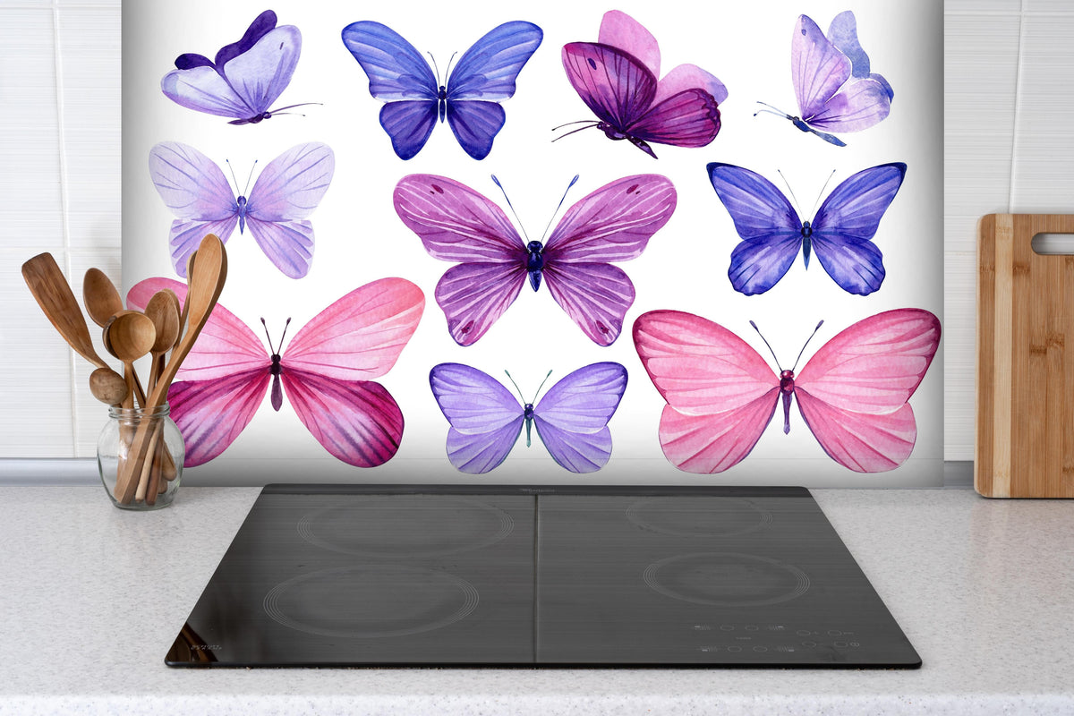 Spritzschutz - Wunderschöne Schmetterlinge auf weißem Hintergrund hinter einem Cerankochfeld zwischen Holz-Kochutensilien
