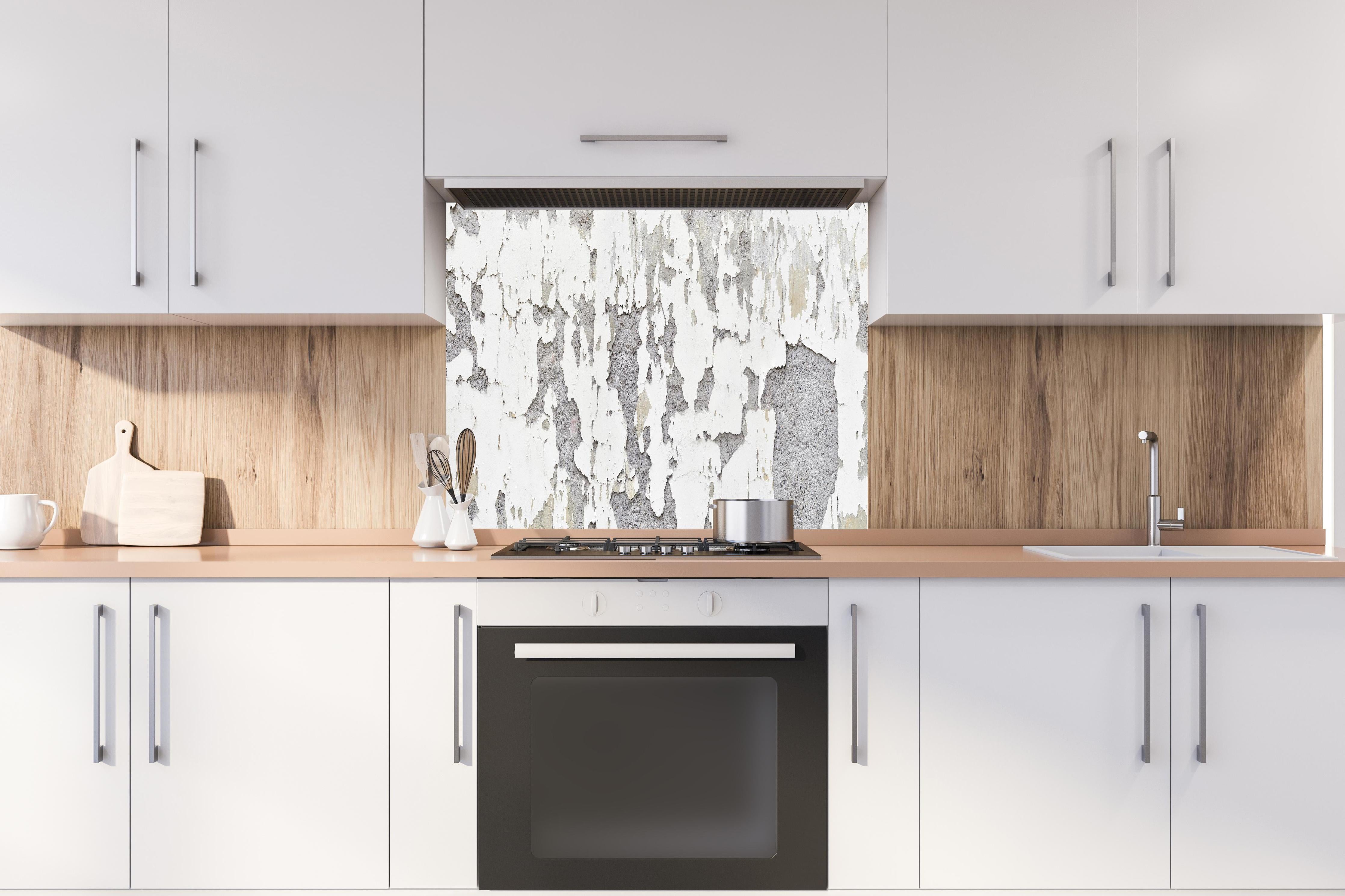 Spritzschutz - Zerplatze Fassade eines alten Hauses hinter einem Cerankochfeld zwischen Holz-Kochutensilien
